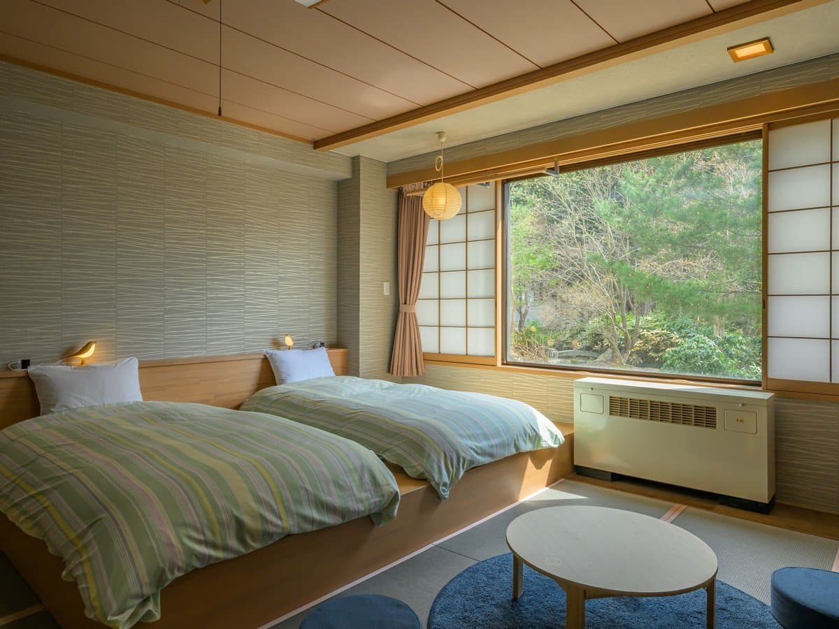 Japanese-style twin room with shoji screens and a large window overlooking the garden at Zao Onsen