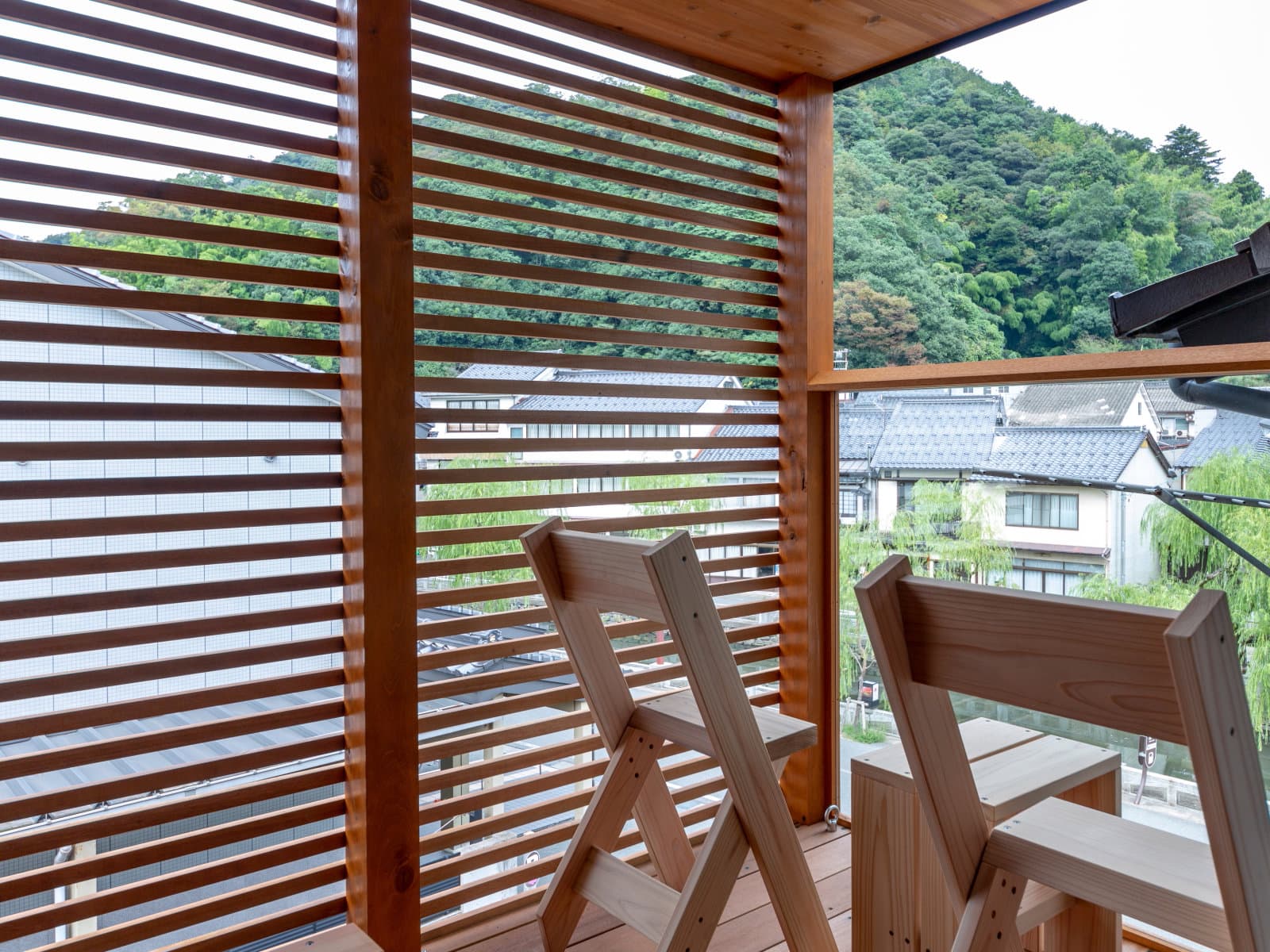 Private wood-slat terrace overlooking the onsen town rooftops and green mountains, Kawaguchiya Honkan, Kinosaki Onsen