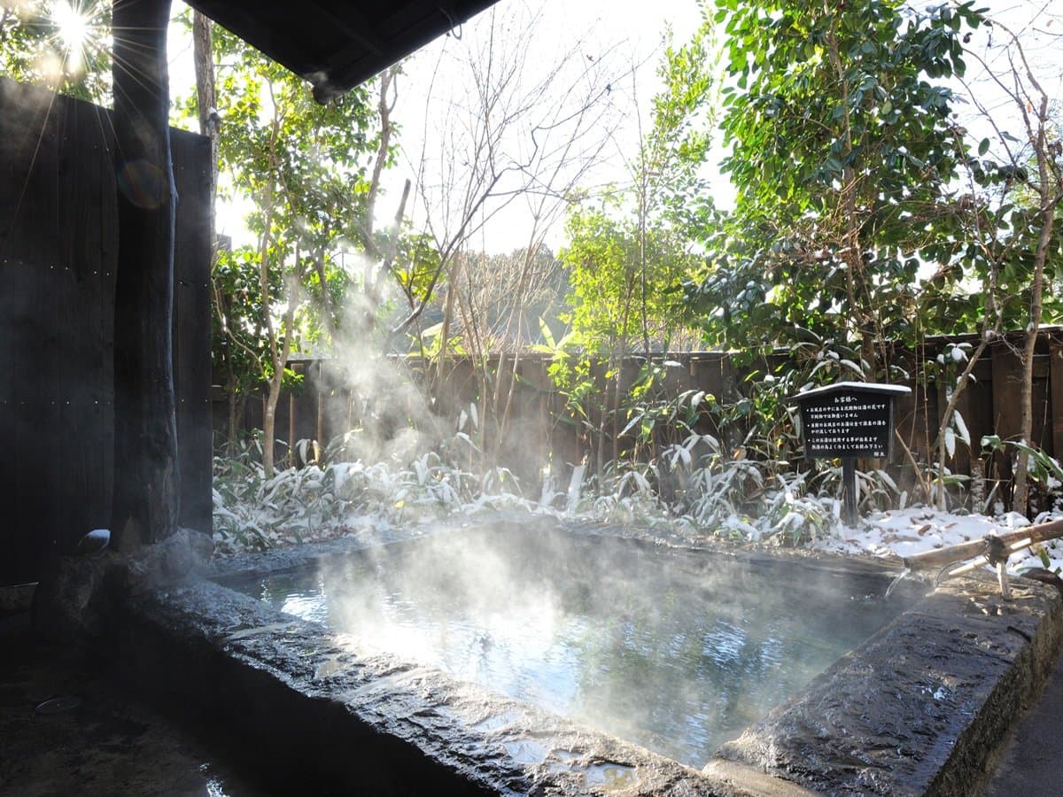 Outdoor rotenburo with rising steam and snow in winter sunlight