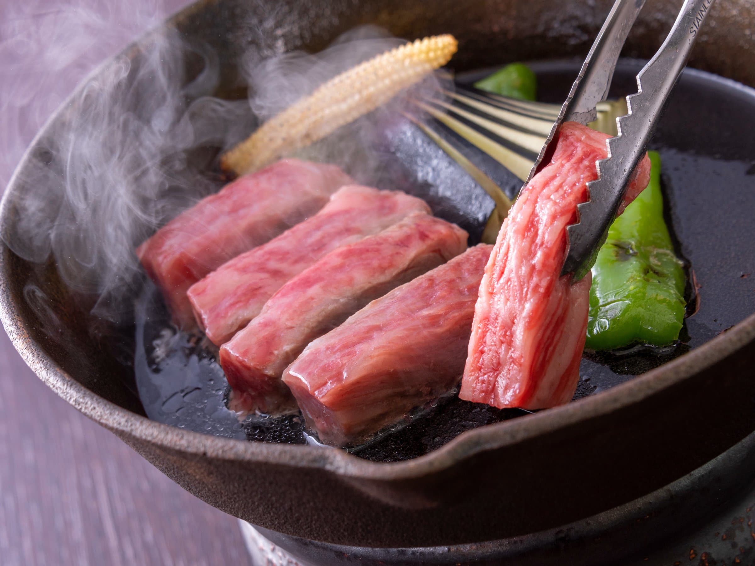 Marbled wagyu beef grilling on a hot iron plate with vegetables, a kaiseki dish at Hotel Hana-An