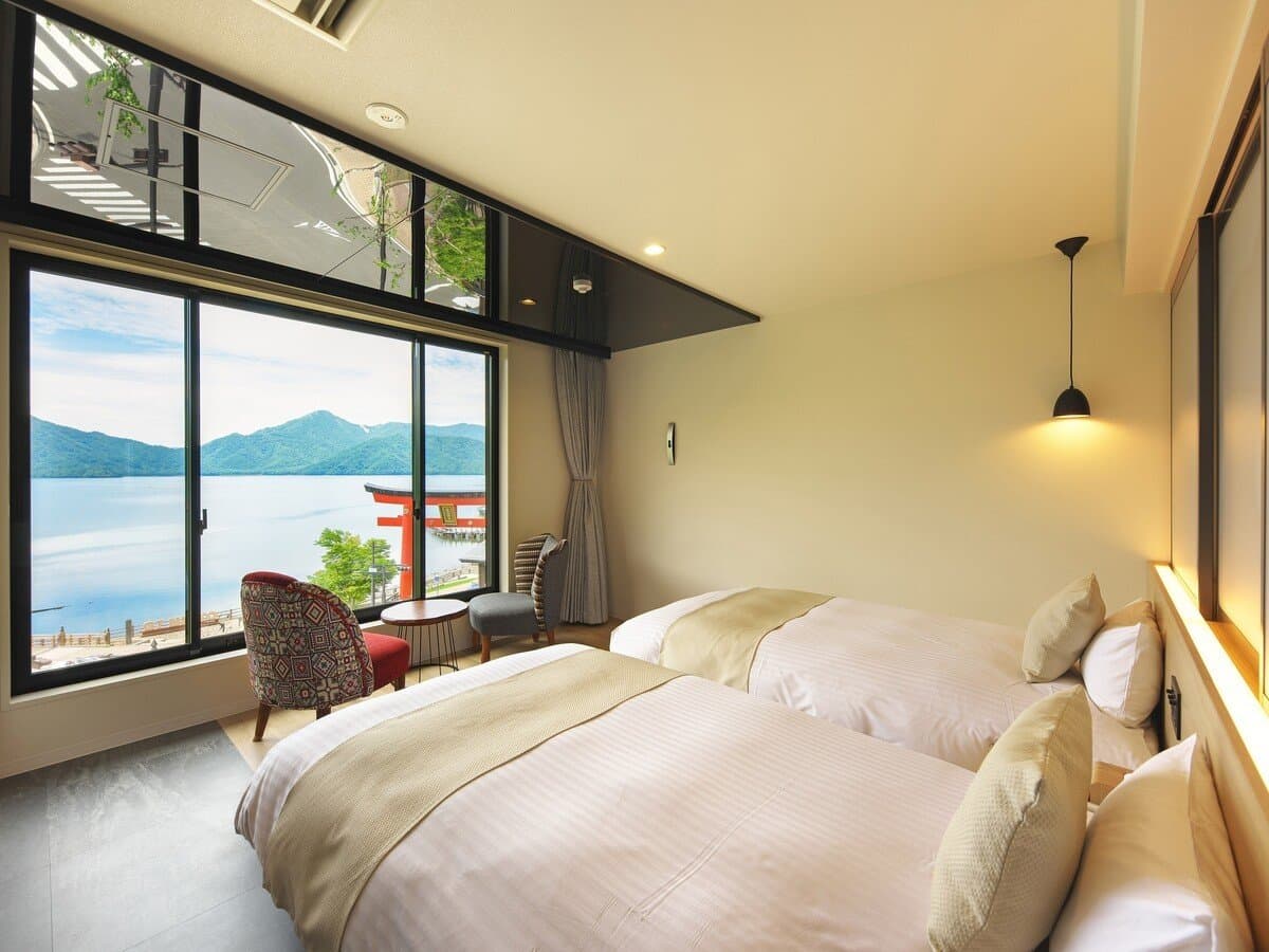Bright twin-bed guest room at Hotel Hana-An facing Lake Chuzenji through a large window