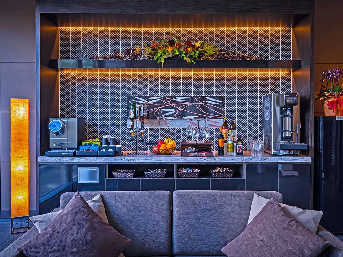 Club lounge service counter with drinks, fruit and an autumn floral display beneath warm indirect lighting, Ryotei Matsubaya, Beppu Onsen