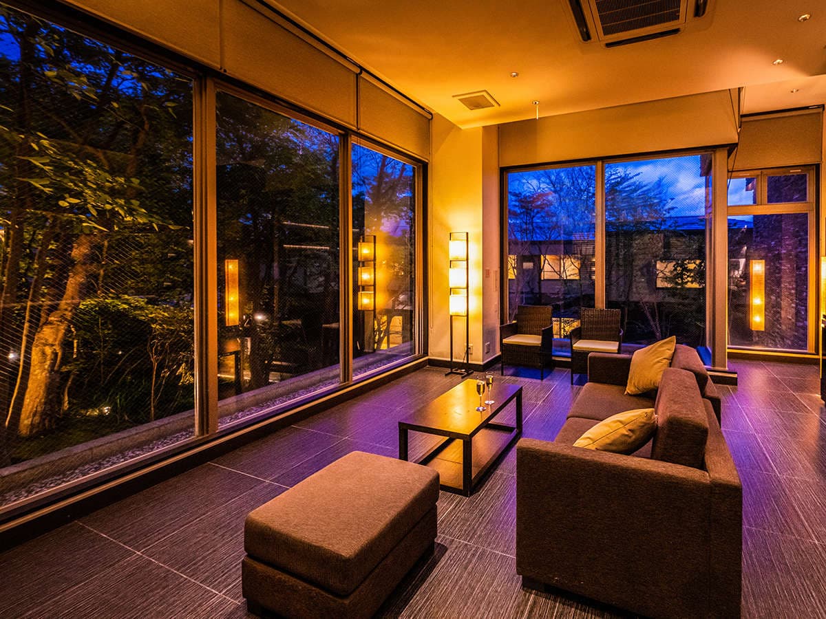 Warmly lit lounge with sofa seating and floor-to-ceiling windows overlooking an illuminated evening garden, Ryotei Matsubaya, Beppu Onsen