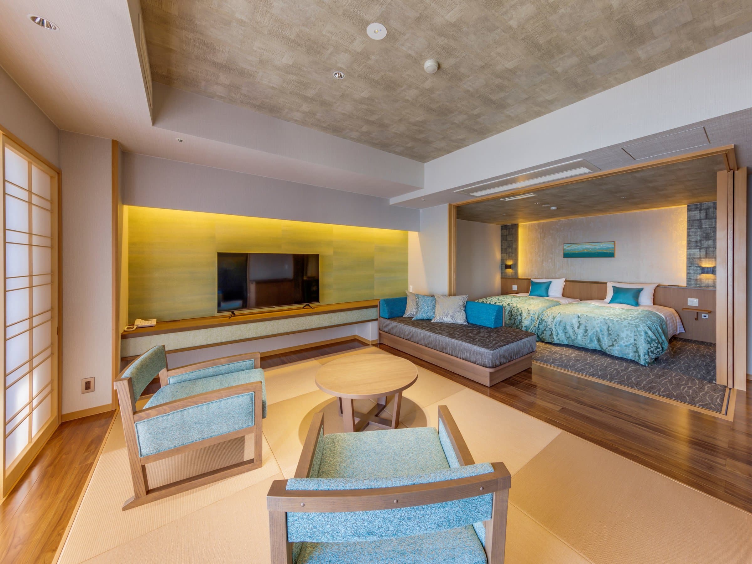 Modern Japanese-Western guest room with twin beds and lounge chairs at Inatori Ginsuiso