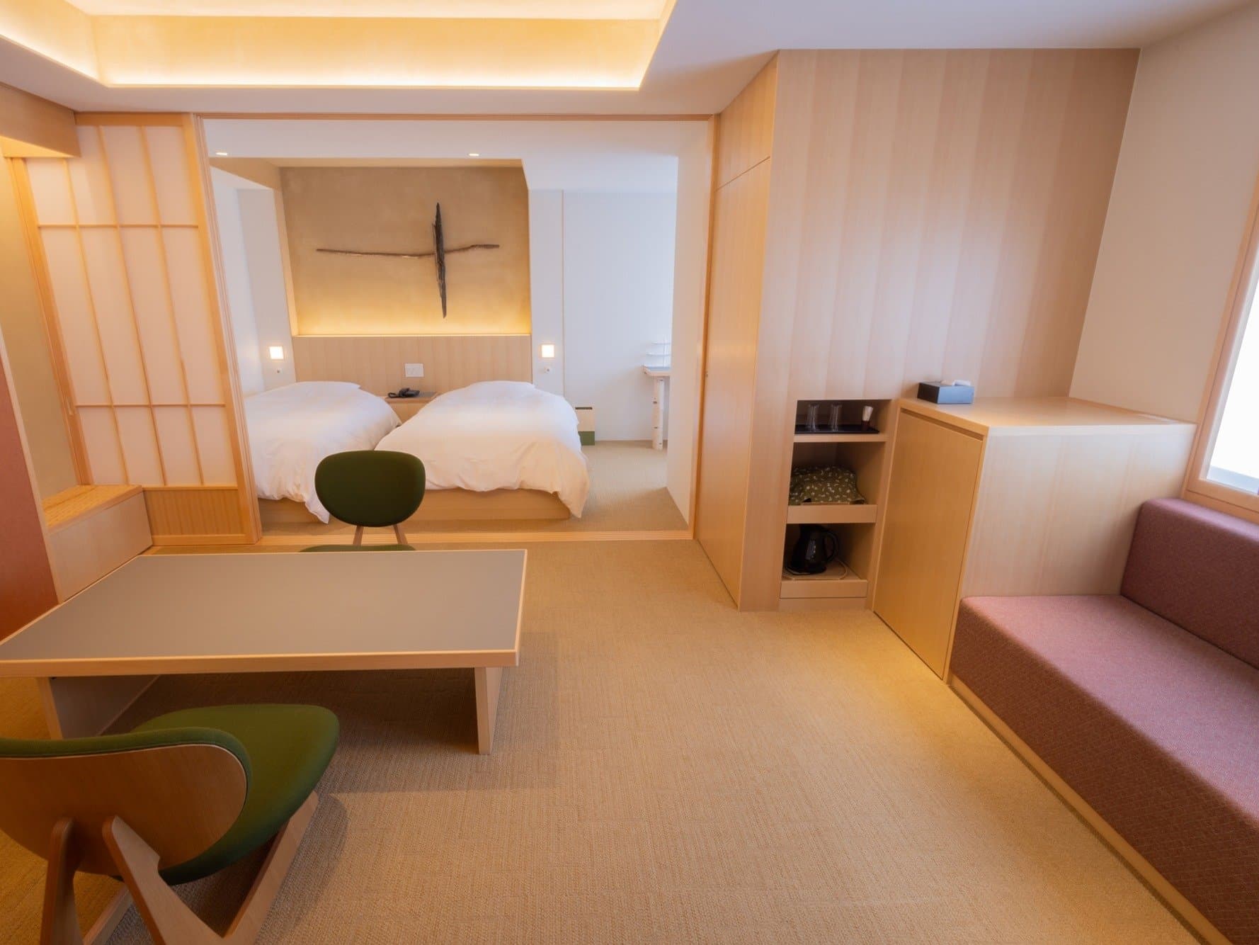 Light wood guest room with twin beds, low table and sofa seating at Kanemidori