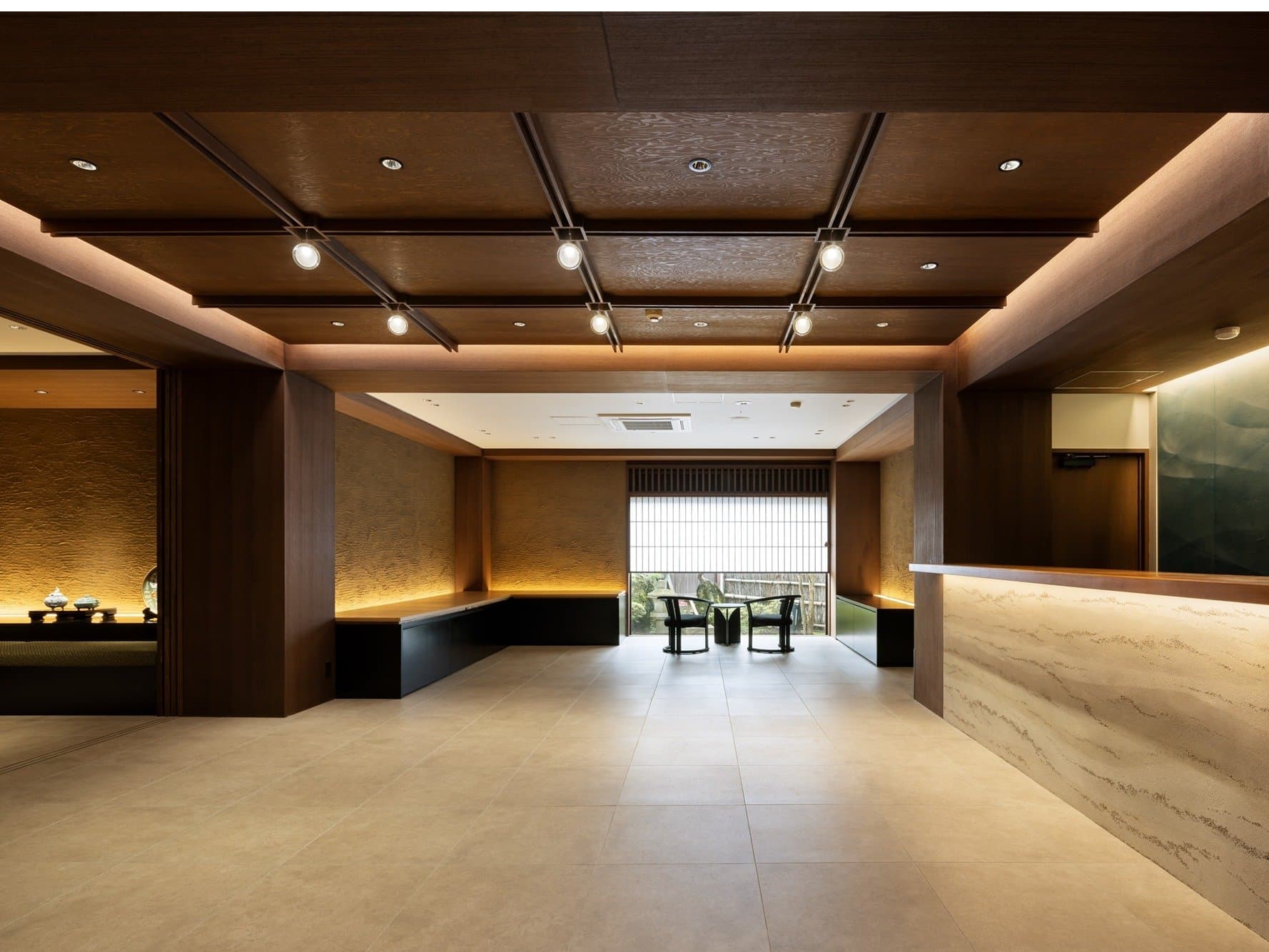 Spacious modern lobby and reception with dark wood coffered ceiling and stone counter at Kanemidori
