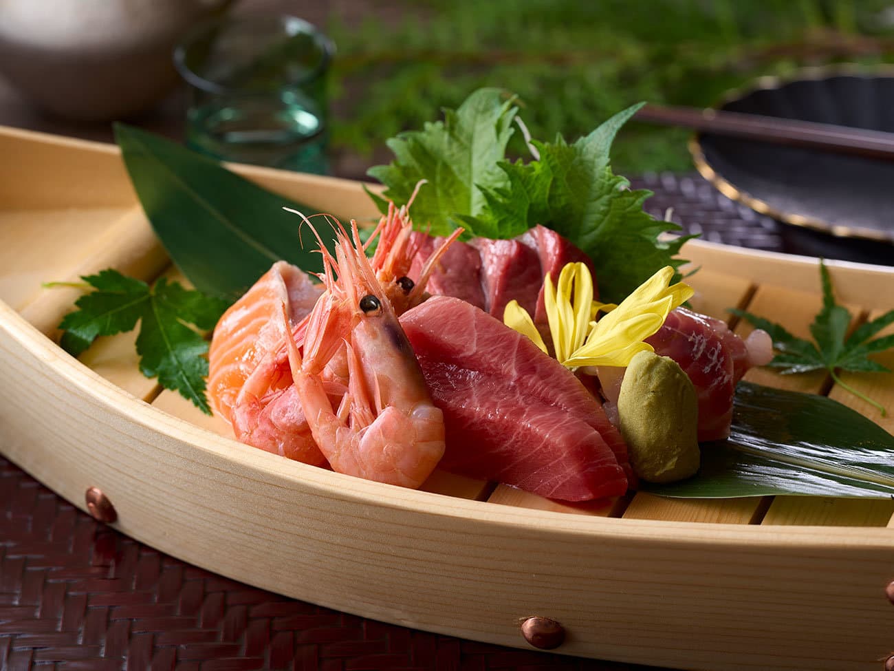 Fresh sashimi platter of tuna, salmon and prawns served on a wooden boat dish