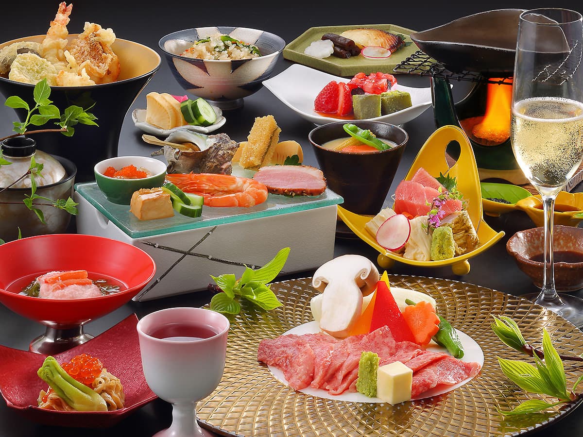 Multi-course kaiseki dinner at Hotel Tsuga no Ki with wagyu, sashimi, simmered dishes and sparkling wine on a dark table