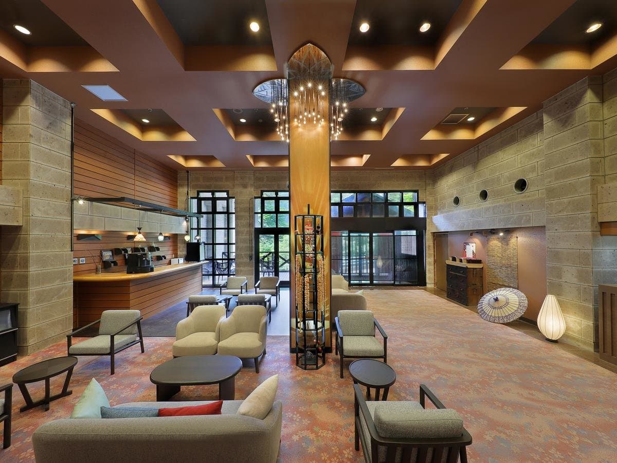 Spacious lobby lounge at Hotel Tsuga no Ki with a hanging chandelier, stone pillars and low seating in Kinugawa Onsen