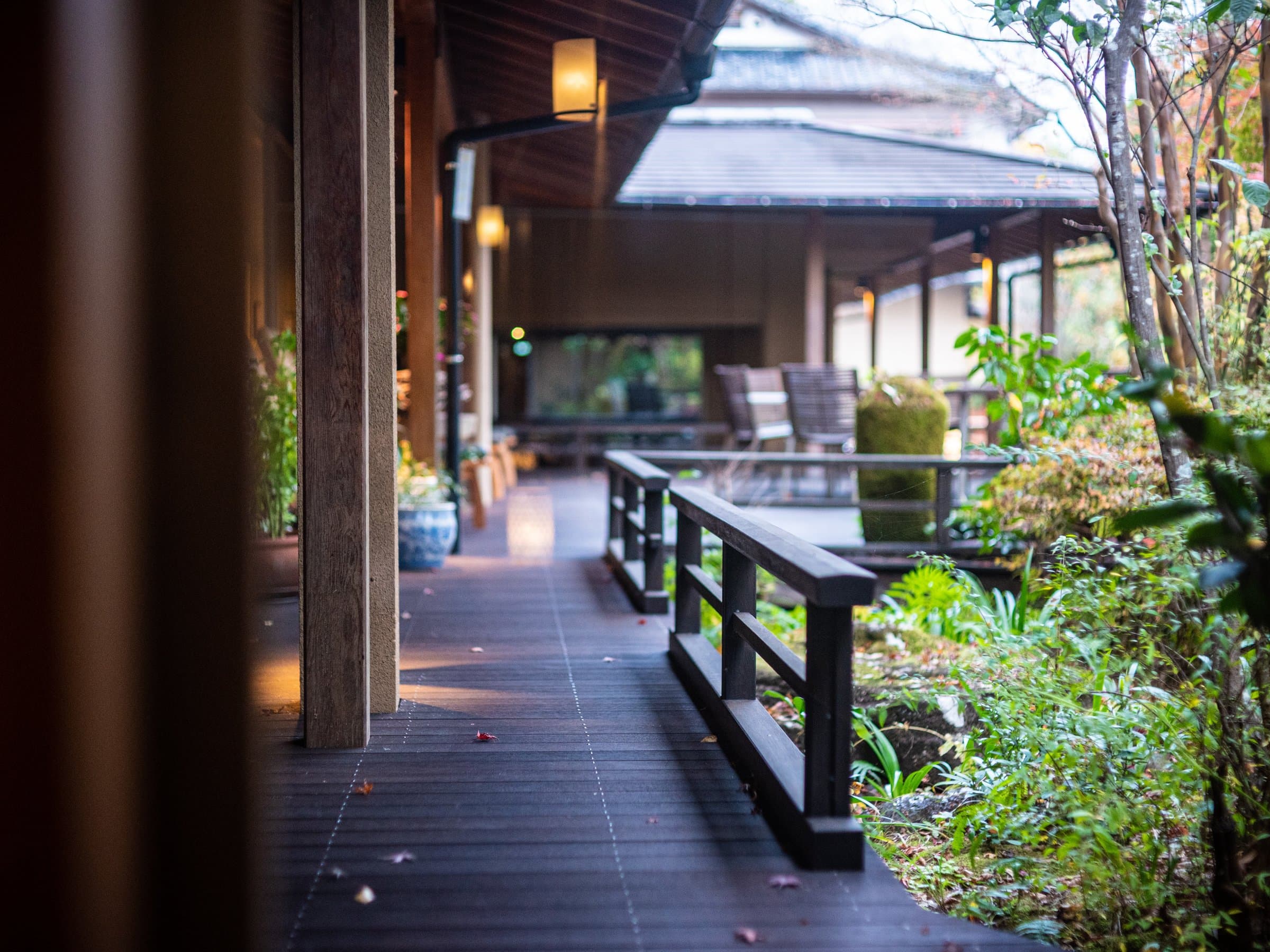 Covered wooden engawa walkway with a balustrade overlooking the lush garden at Sagasawakan ryokan, Izu