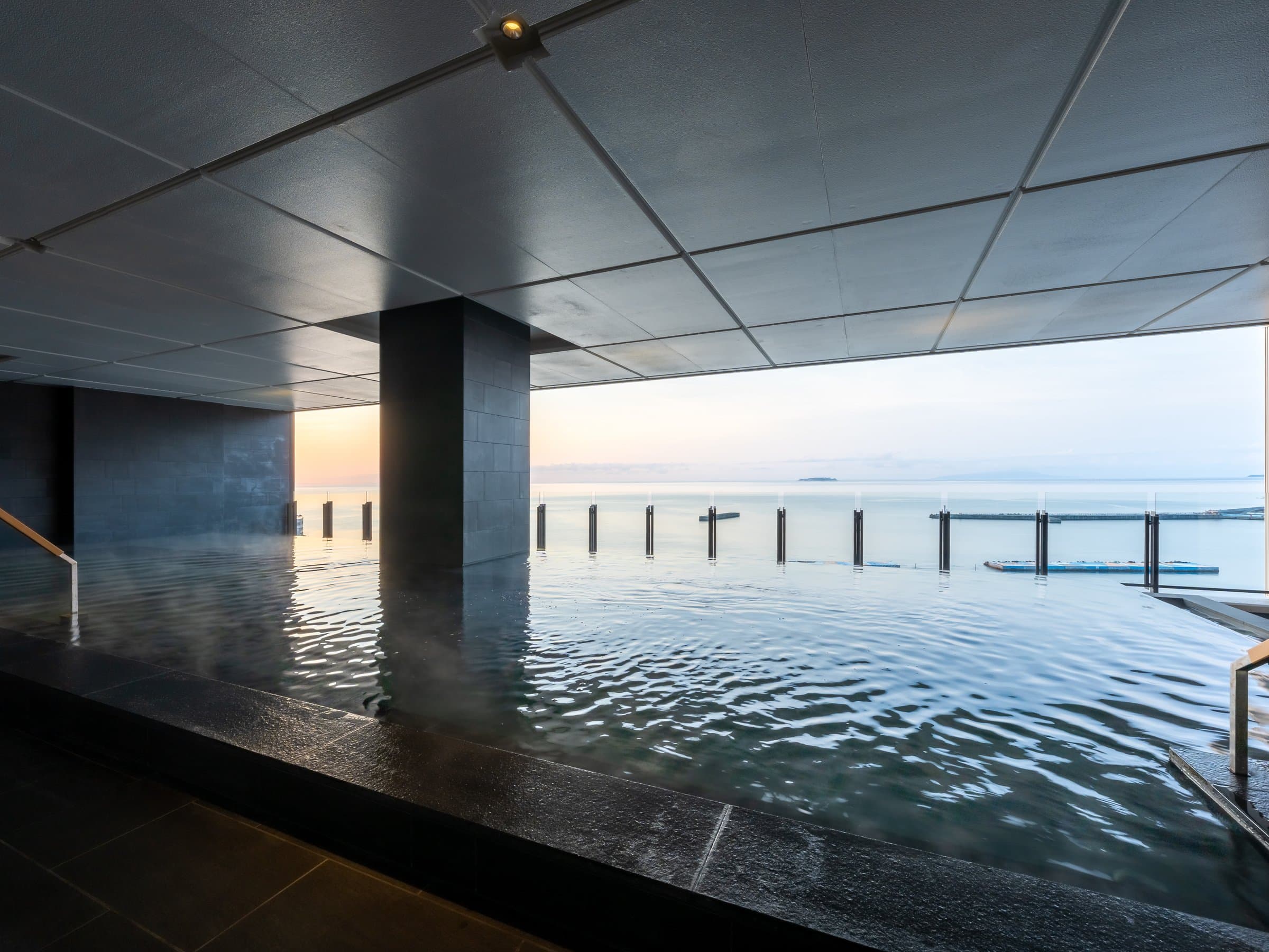 Indoor infinity onsen bath at Pearl Star Hotel Atami overlooking the sea at sunset