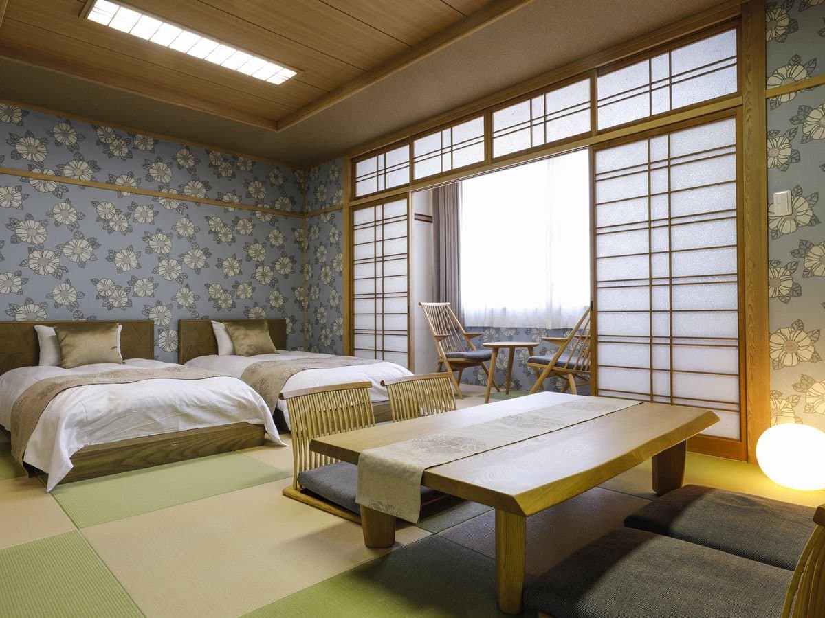 Spacious Japanese twin-bed guest room with shoji screens and tatami floor at Hotel Katsuragi, Dogo Onsen