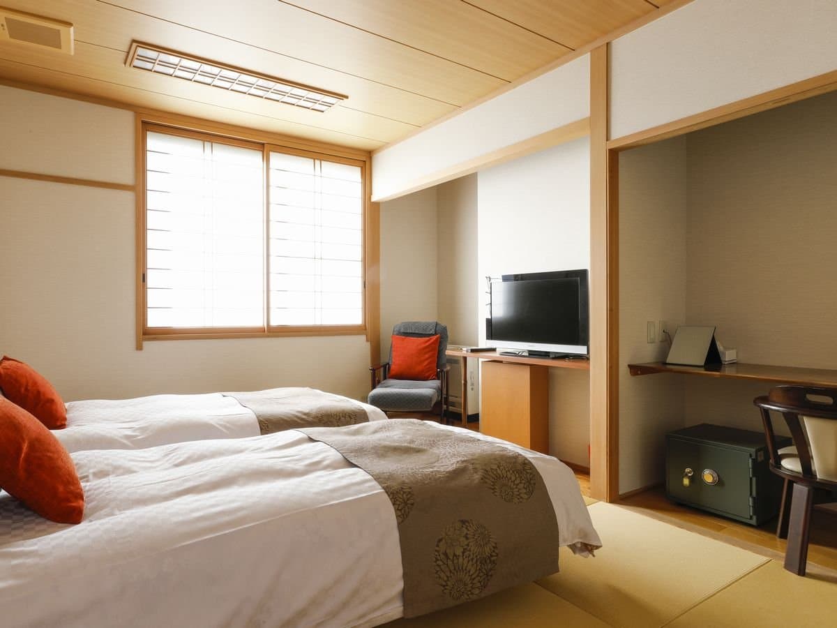 Modern Japanese-Western twin room with twin beds and writing desk at Hotel Katsuragi, Dogo Onsen