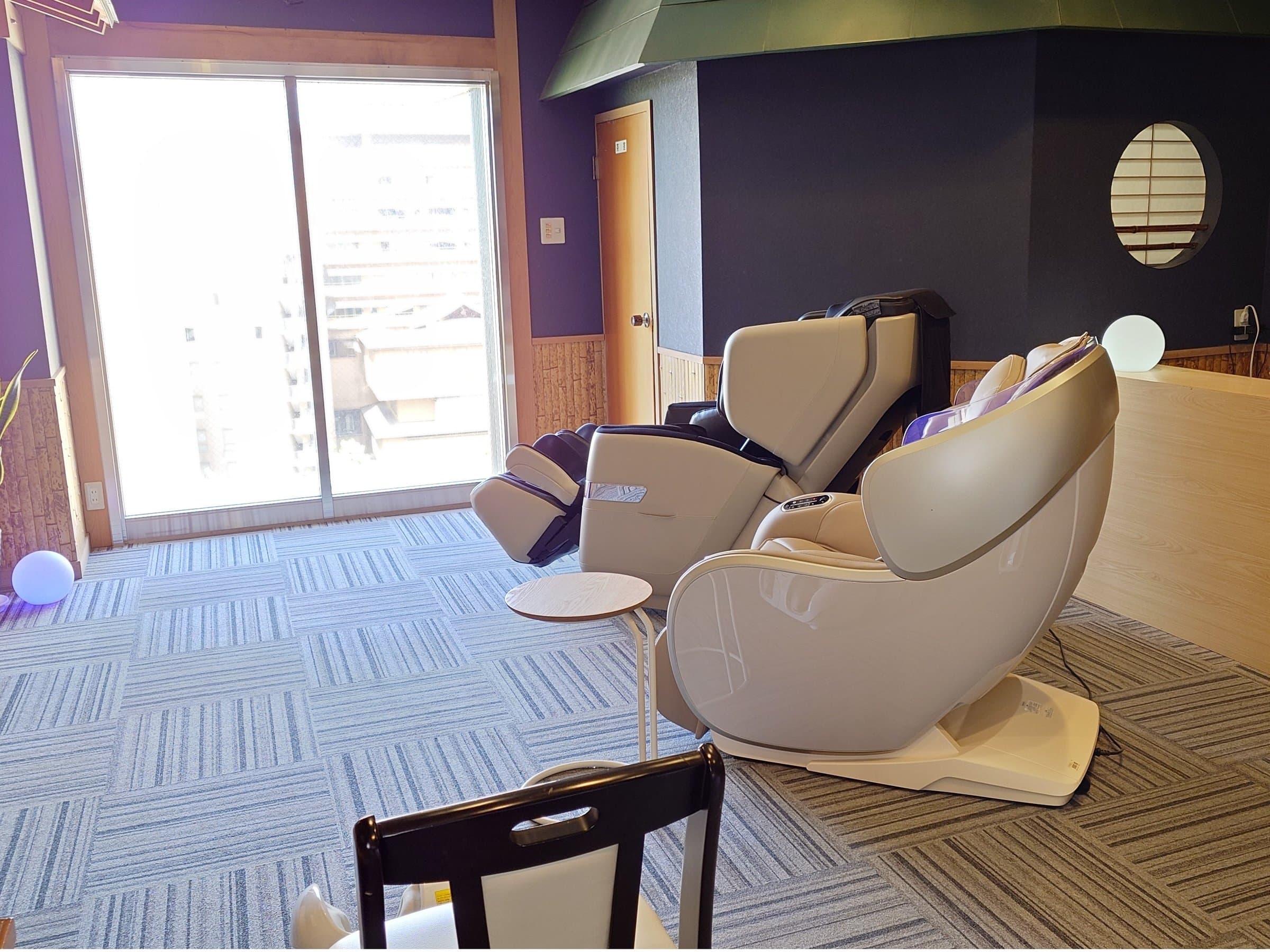 Relaxation lounge with massage chairs and a town view at Hotel Katsuragi, Dogo Onsen
