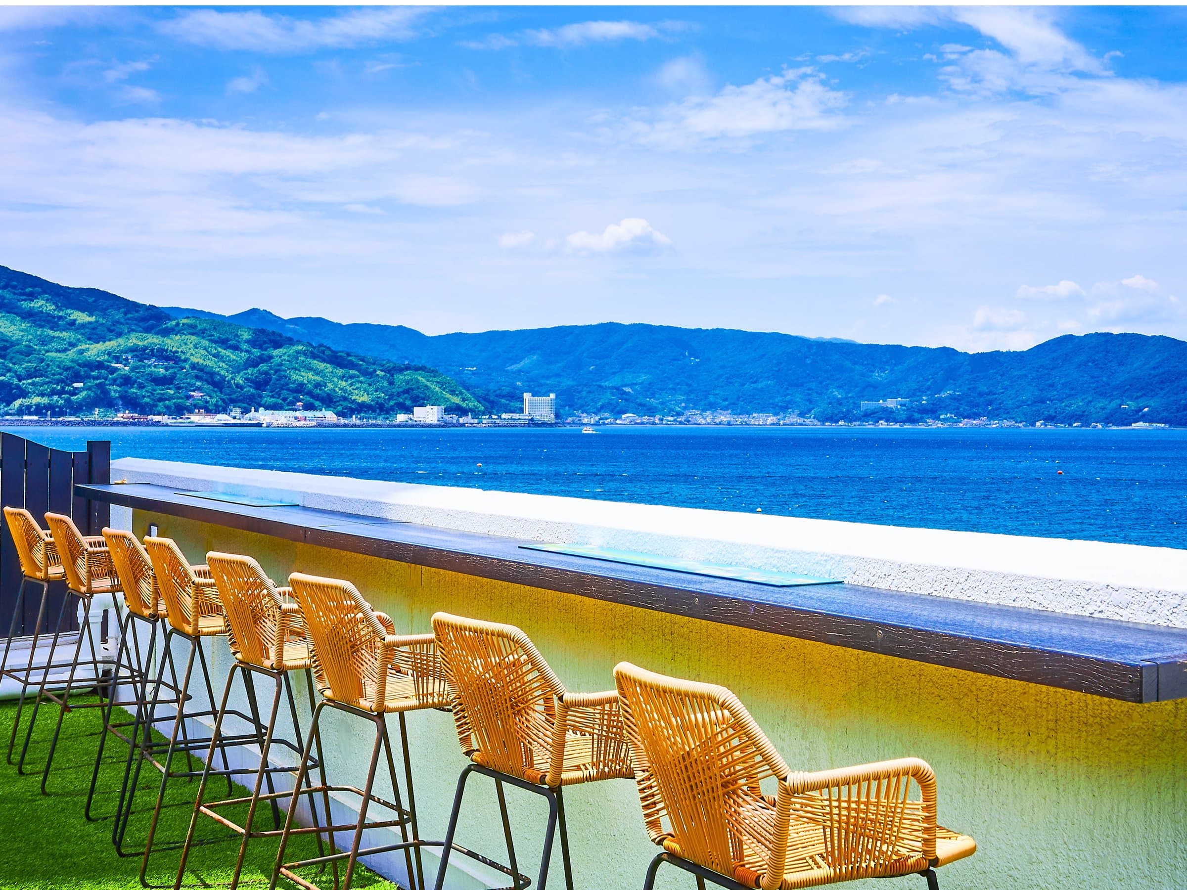 Rooftop sky bar counter with rattan stools facing the open Pacific in Izu