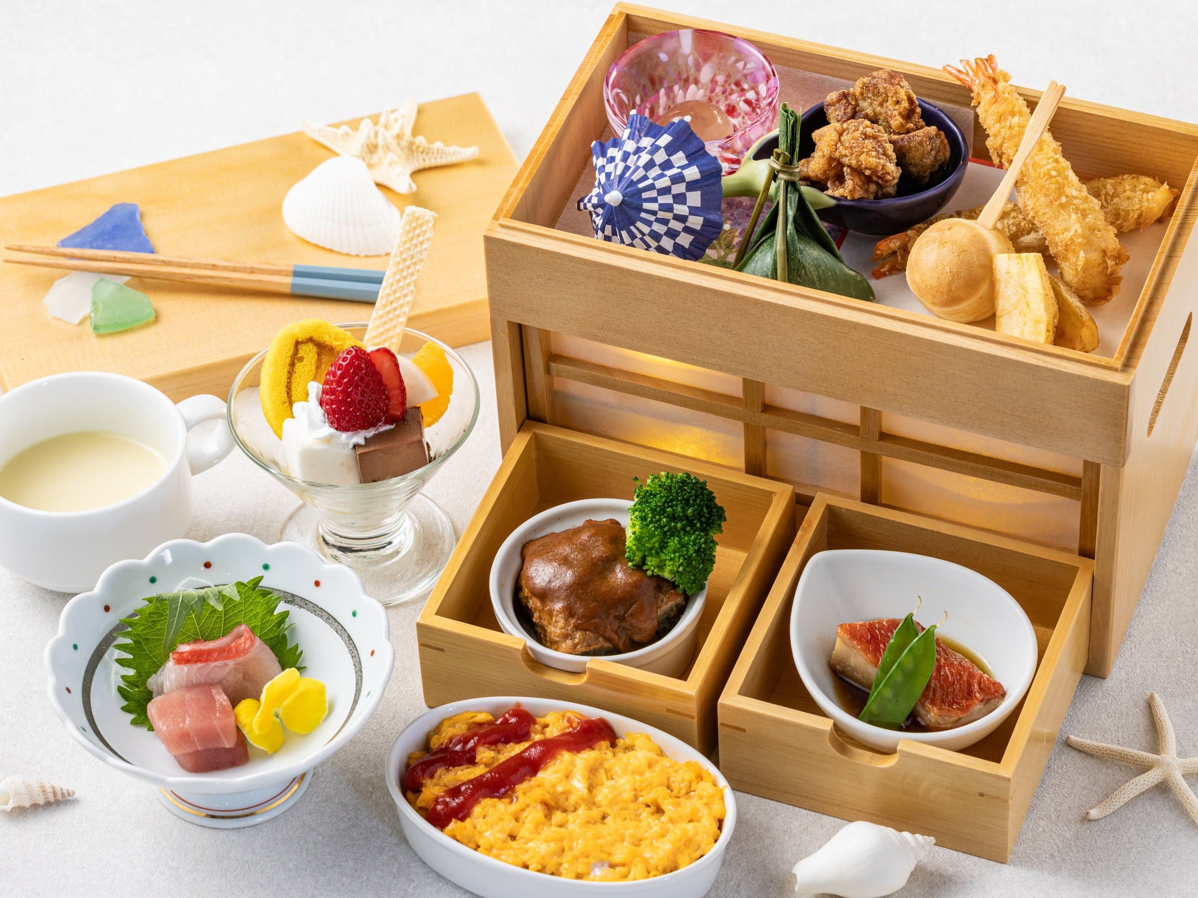 Japanese breakfast served in a tiered wooden box with sashimi, tempura, egg and dessert
