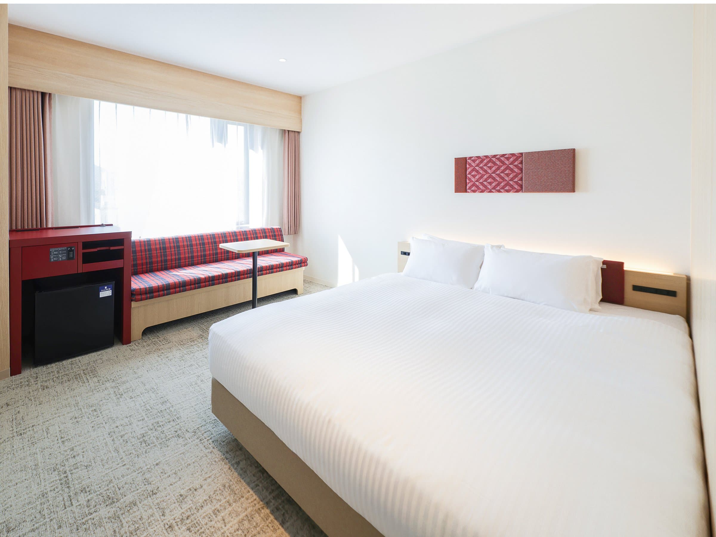 Bright guest room with double bed and red-accent window sofa at HOTEL AMANEK Hida Takayama