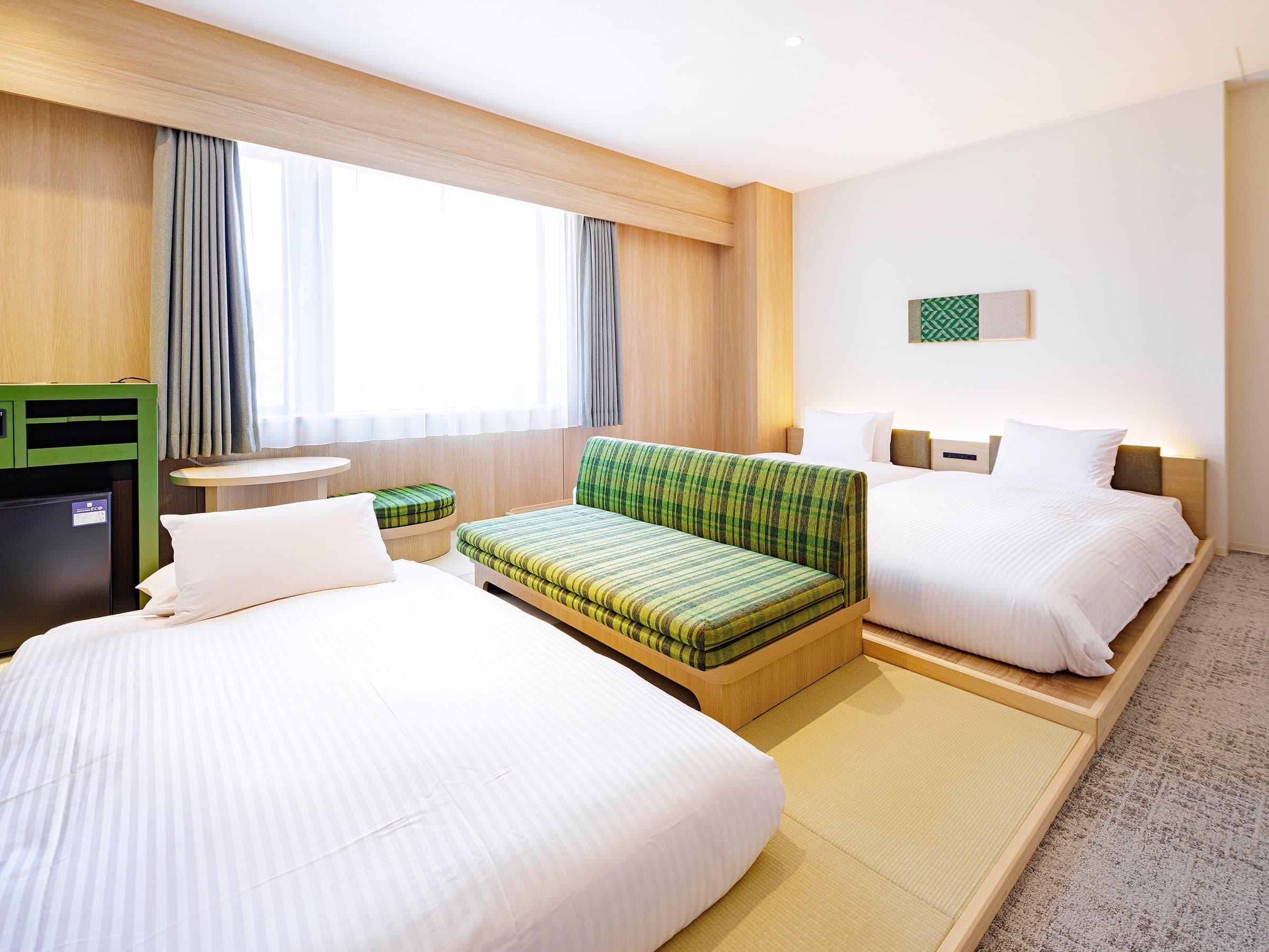 Guest room with twin beds, green plaid sofa and tatami platform at HOTEL AMANEK Hida Takayama