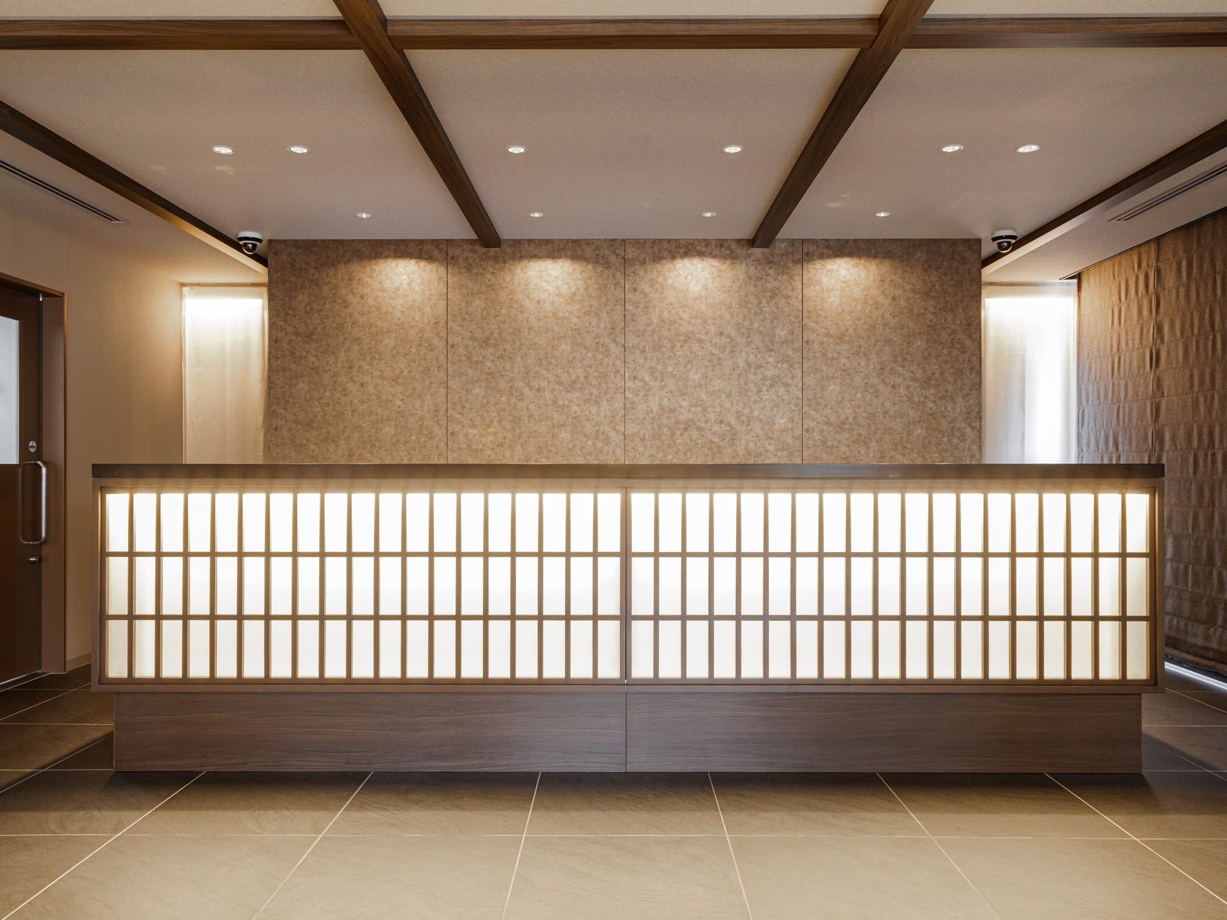 Front desk with backlit shoji-style lattice and wood-beam ceiling in the lobby