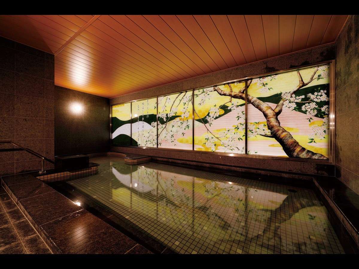 Stone-lined indoor onsen bath glowing with a backlit cherry-blossom panel along the wall at Daiwa Roynet Hotel Nara