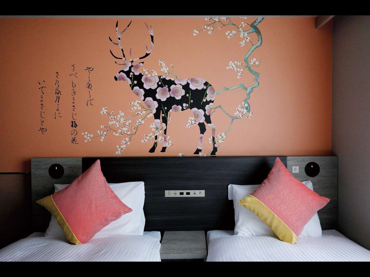 Twin beds beneath a coral wall mural of a flower-patterned Nara deer with classical calligraphy at Daiwa Roynet Hotel Nara