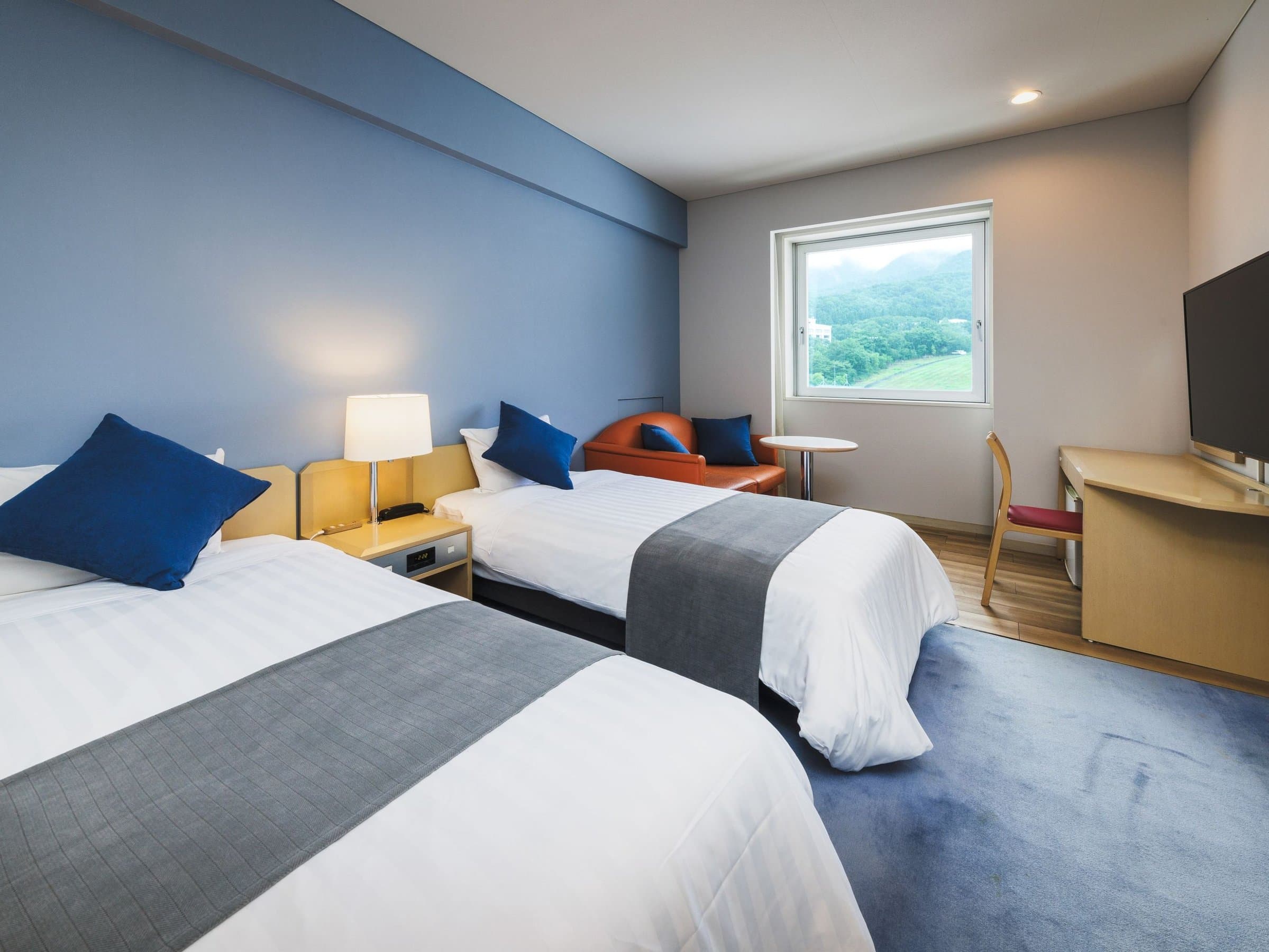 Renovated mountain-view twin room with blue accents, twin beds and a window onto the Zao hills