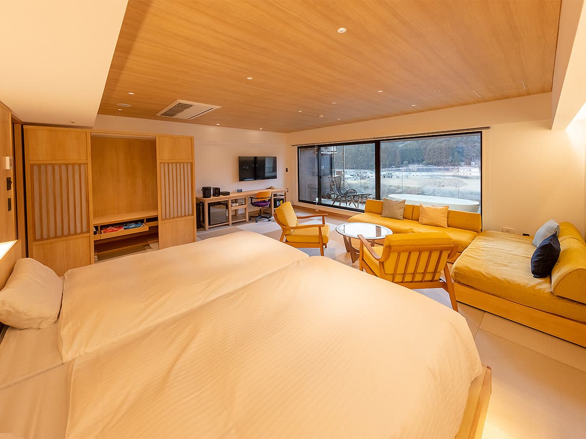 Spacious wa-modern guest room with king bed, lounge sofa, private terrace bath and river-valley view at Mikazuki