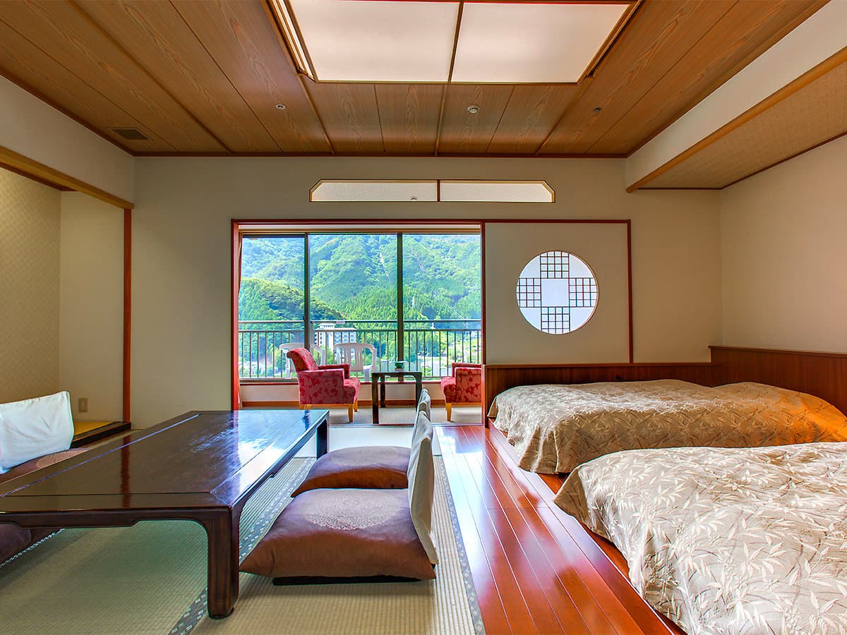 Japanese-Western guest room with twin beds, low table, round shoji window and Kinugawa mountain view