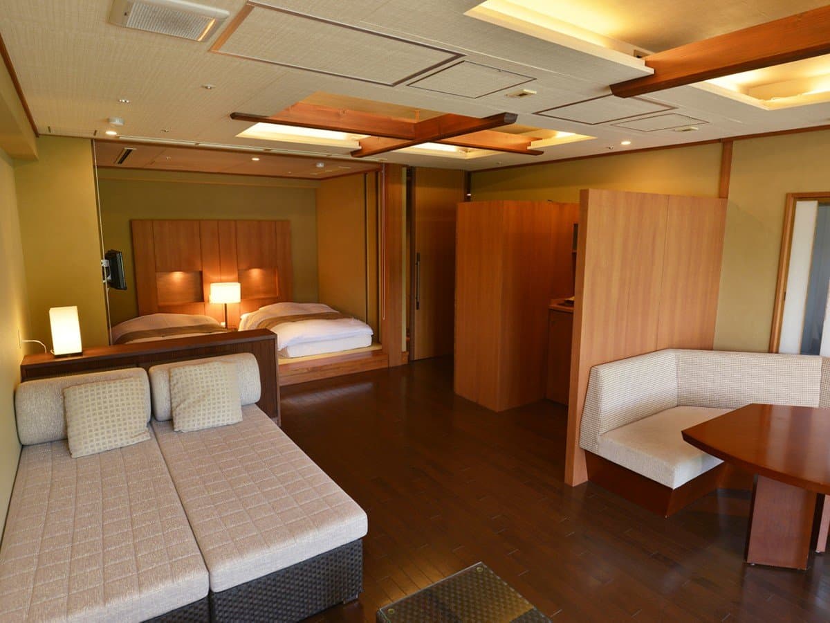 Premium Japanese-Western suite with bed, sofa lounge and dark wood floor at Hotel New Mitoya, Akiu Onsen