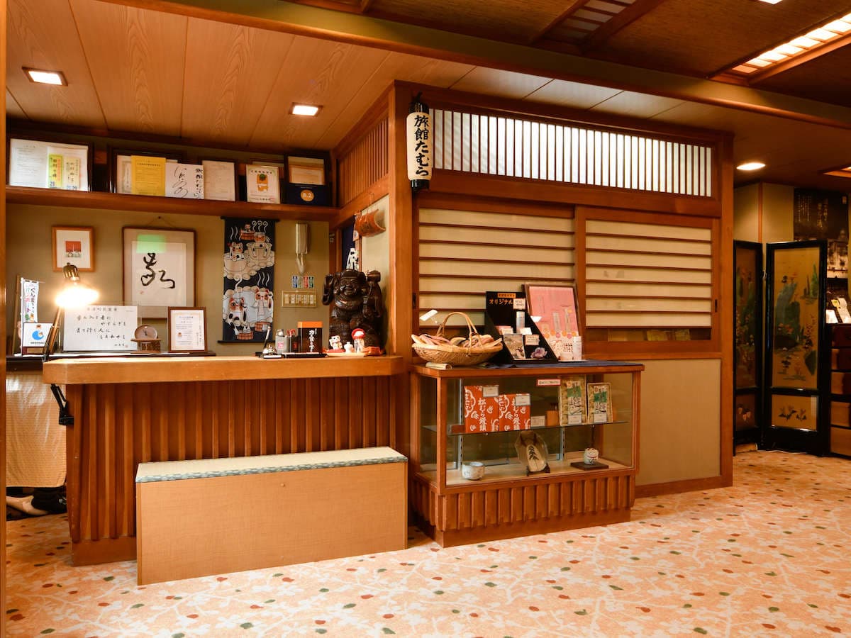 Front desk and lobby at Ryokan Tamura with a wooden reception counter and traditional decor