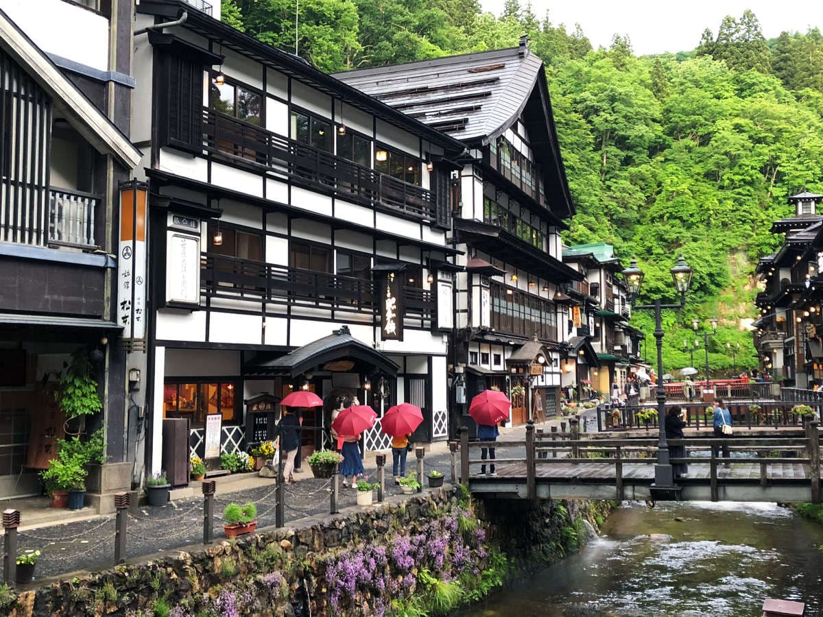 Daytime view of the historic wooden inns lining the Ginzan Onsen canal where Showakan stands in Yamagata