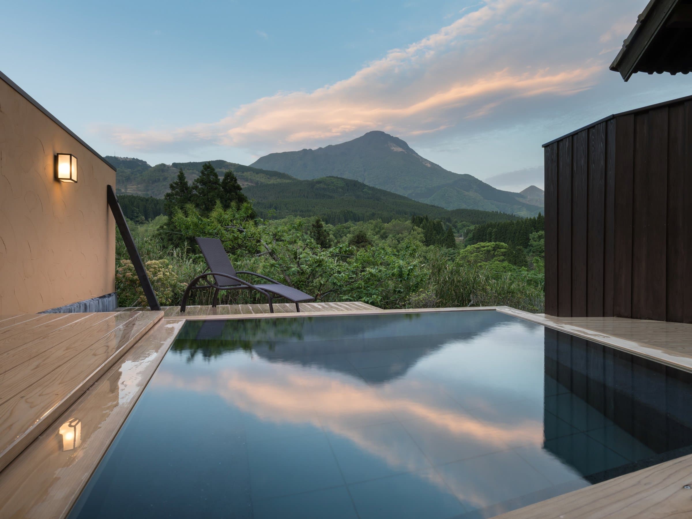 Private open-air infinity onsen bath reflecting the sunset sky with Mount Yufu beyond at Ikkoten in Yufuin
