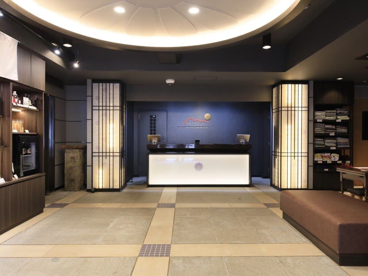 Modern front desk and reception lobby at Hotel Kikunoya with navy walls and washi-paper lantern panels on Miyajima