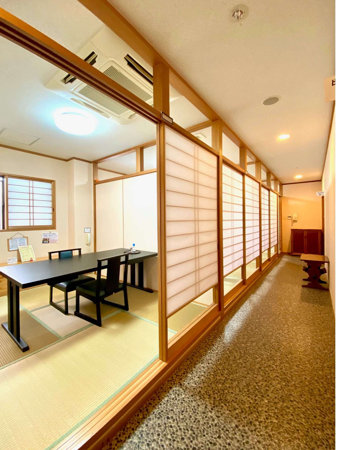 Private tatami dining room beside a shoji-screen interior hallway at Ryokan Tsukimiso, Ibusuki