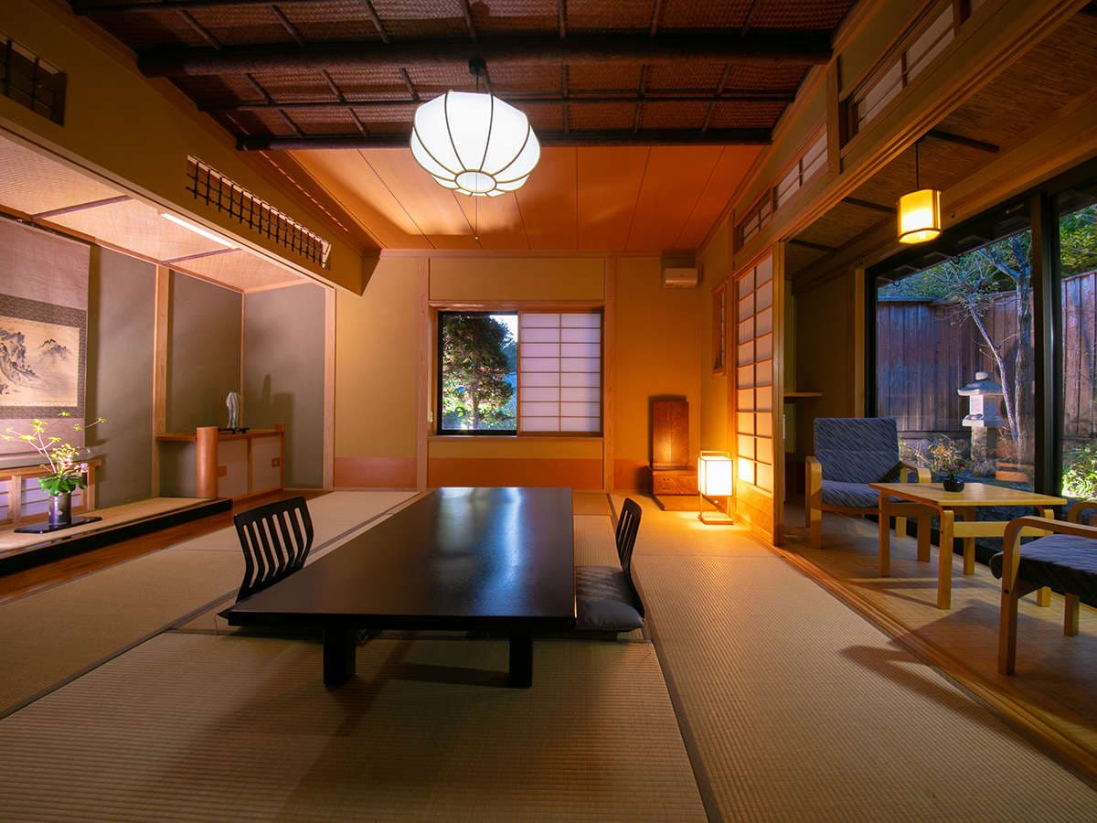 Tatami lounge and dining room lit by hanging lanterns with garden views at Oyado Ichizen