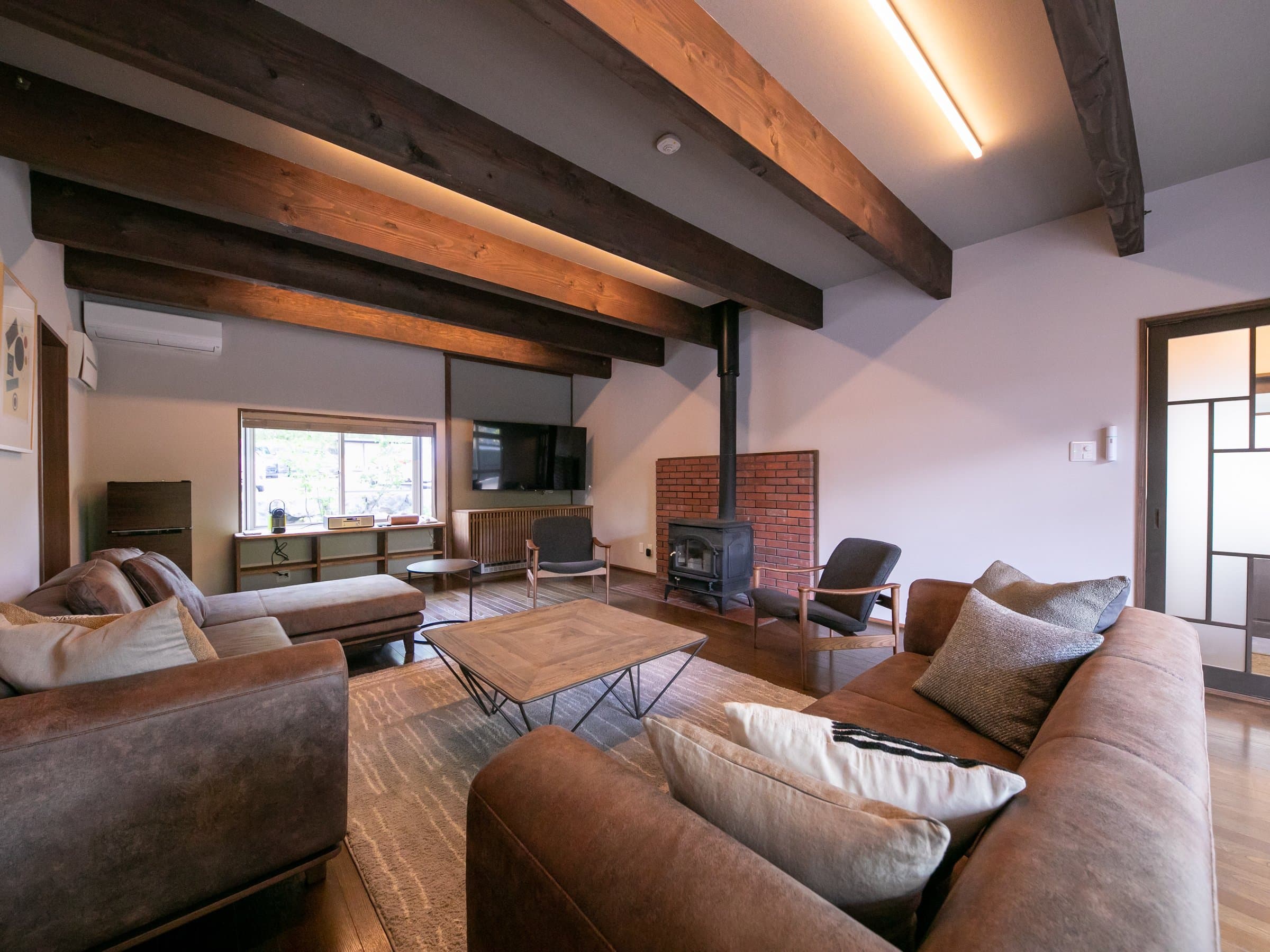 Spacious guest room living area with sofas and large windows opening to the Yufuin countryside