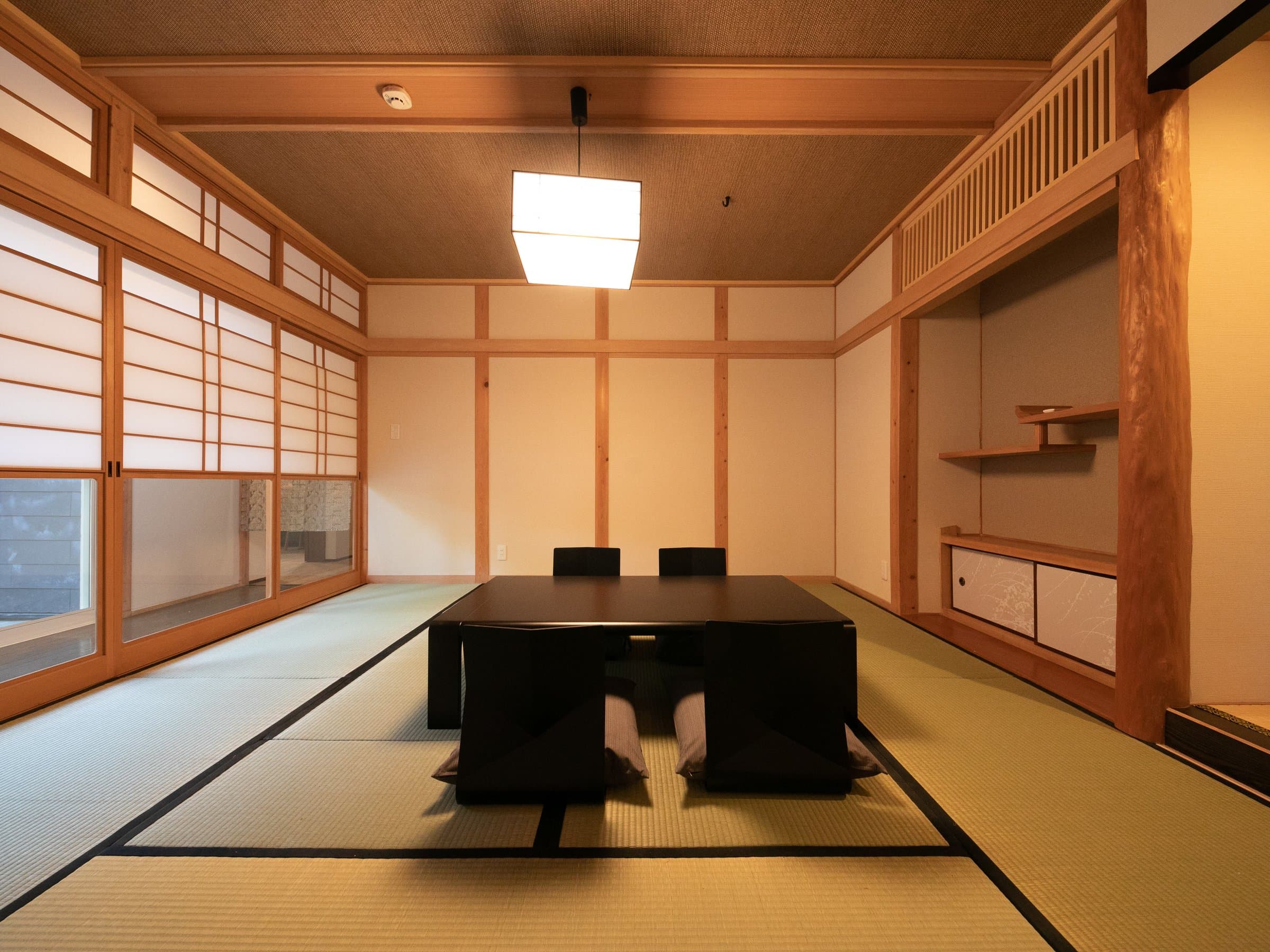 Traditional tatami guest room with shoji screens, low table and tokonoma alcove at Oyado Ichizen