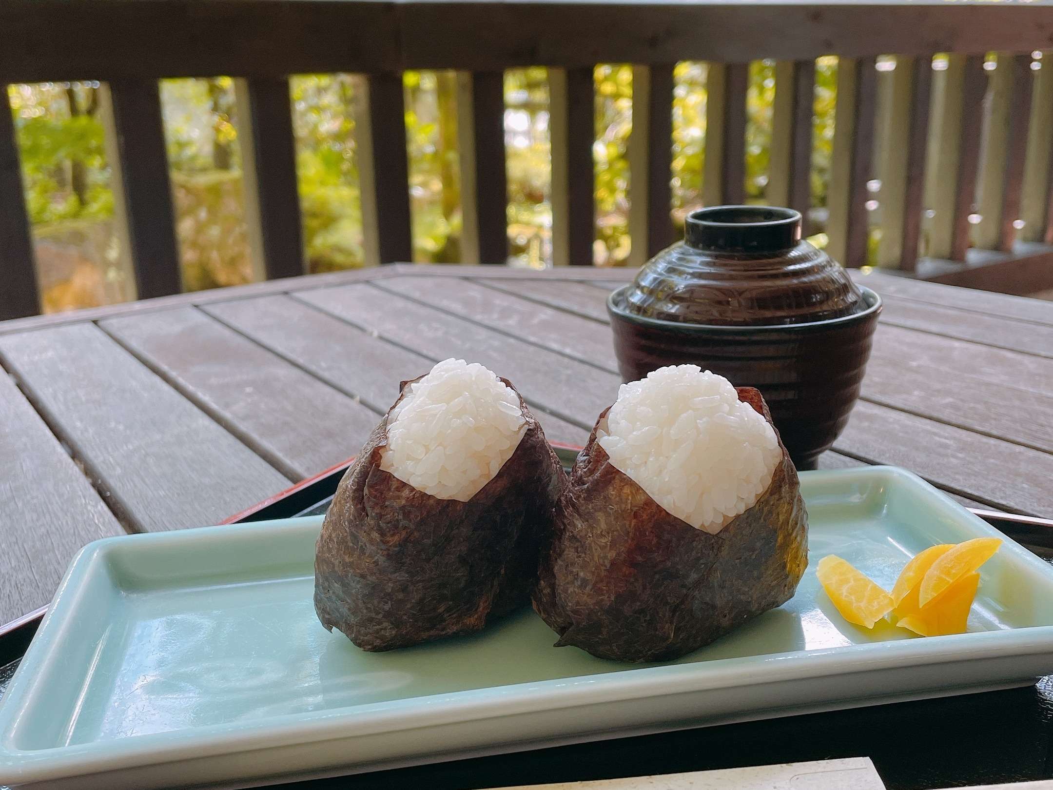 Breakfast rice onigiri and miso soup served on a terrace overlooking autumn greenery at Hodakaso Yamano Iori