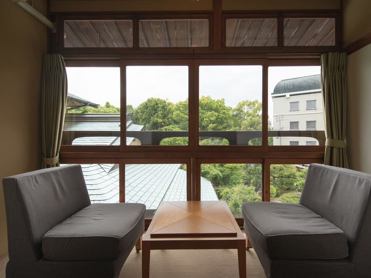 Window seating corner of a Umenoya guest room overlooking the green of Dogo Park and the inn's tiled roofline