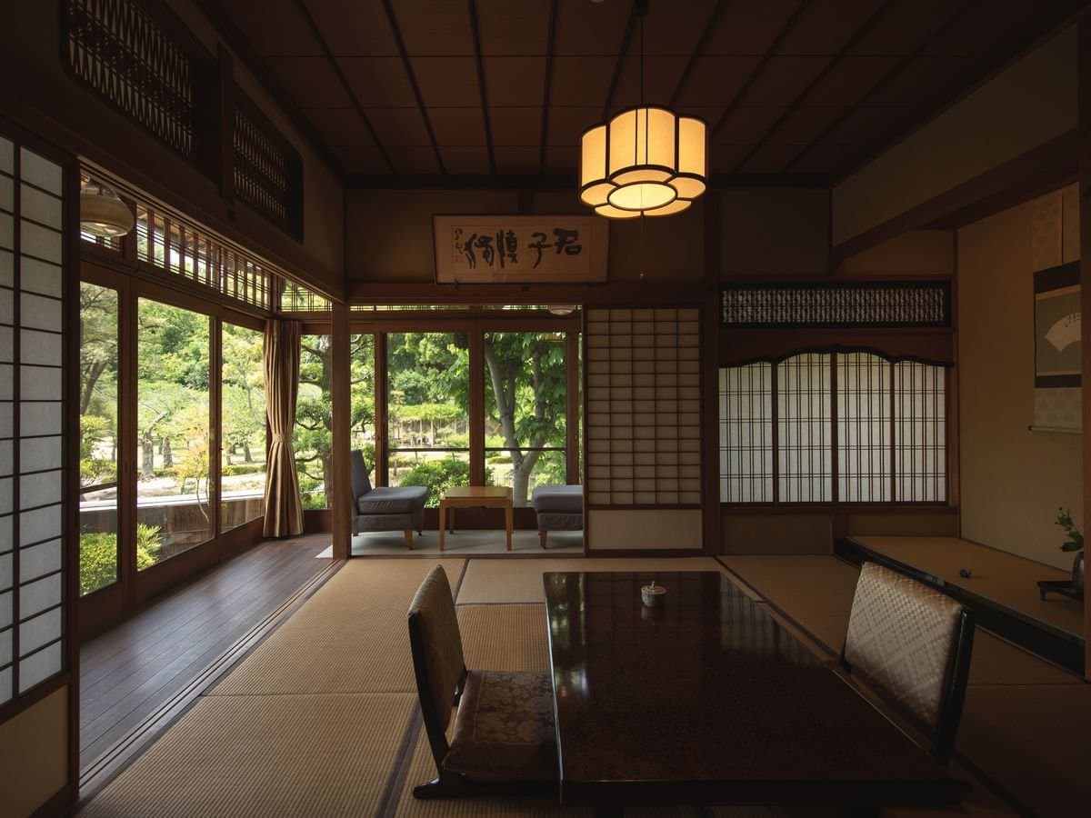 Tatami guest room at Umenoya with a low lacquer table, calligraphy panel and garden view through sliding glass doors