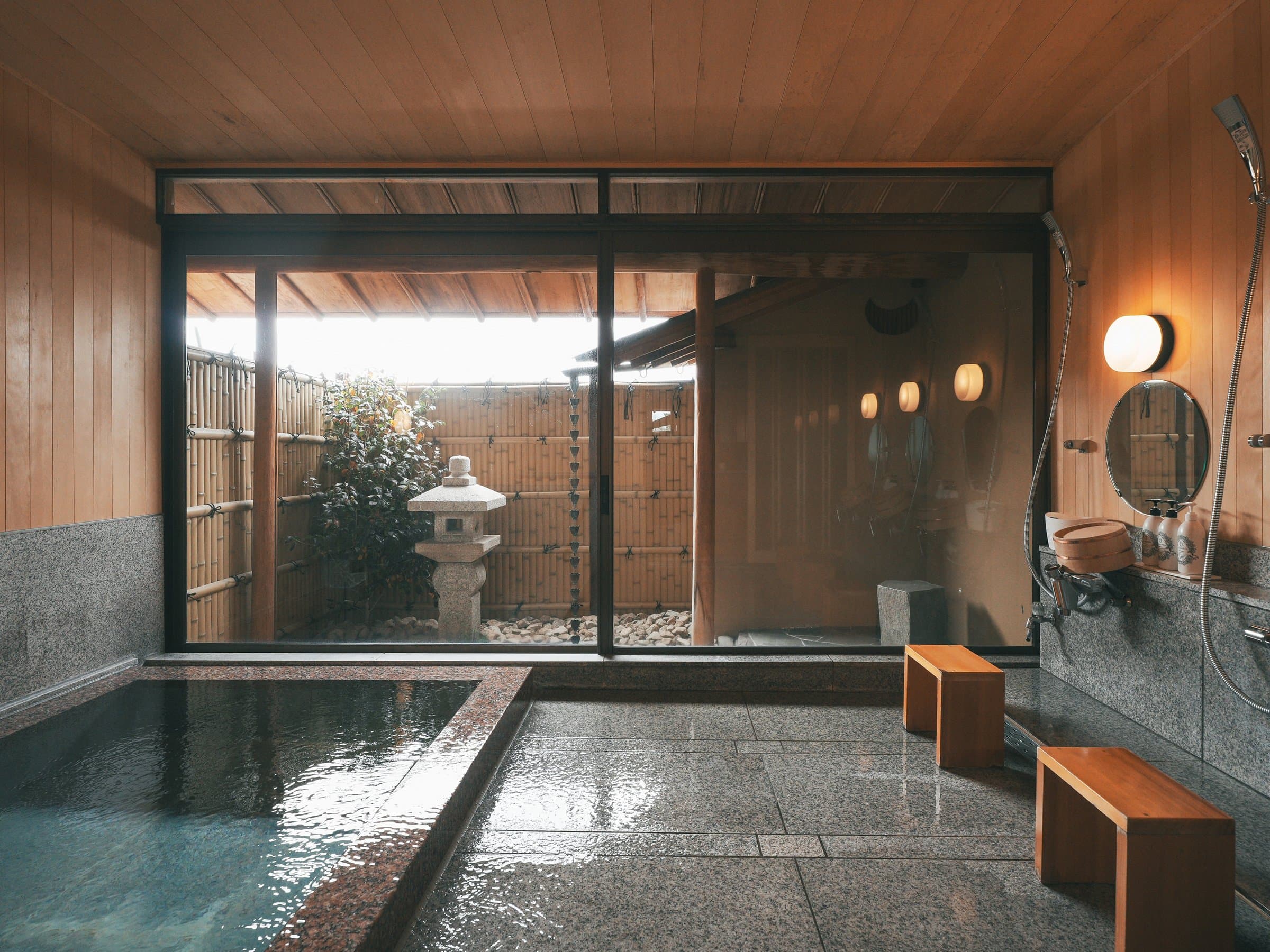 Hanamo-no-Yu indoor stone bath at Umenoya looking out to a small bamboo-fenced garden with a stone lantern