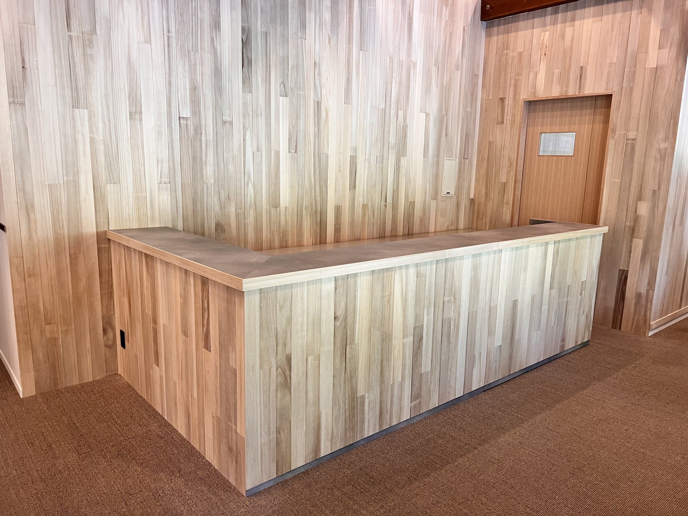 Reception desk clad in pale wood paneling in the entrance area of Yamanote Bettei Hagakure