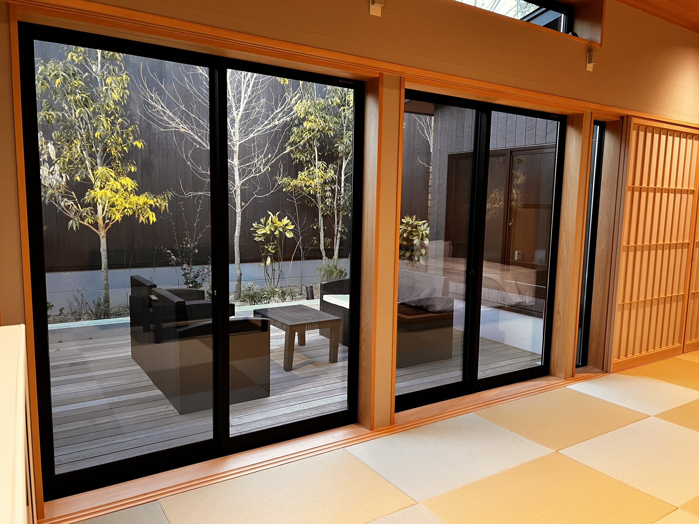 Tatami guest room opening through glass doors onto a private wooden terrace and courtyard garden at Hagakure