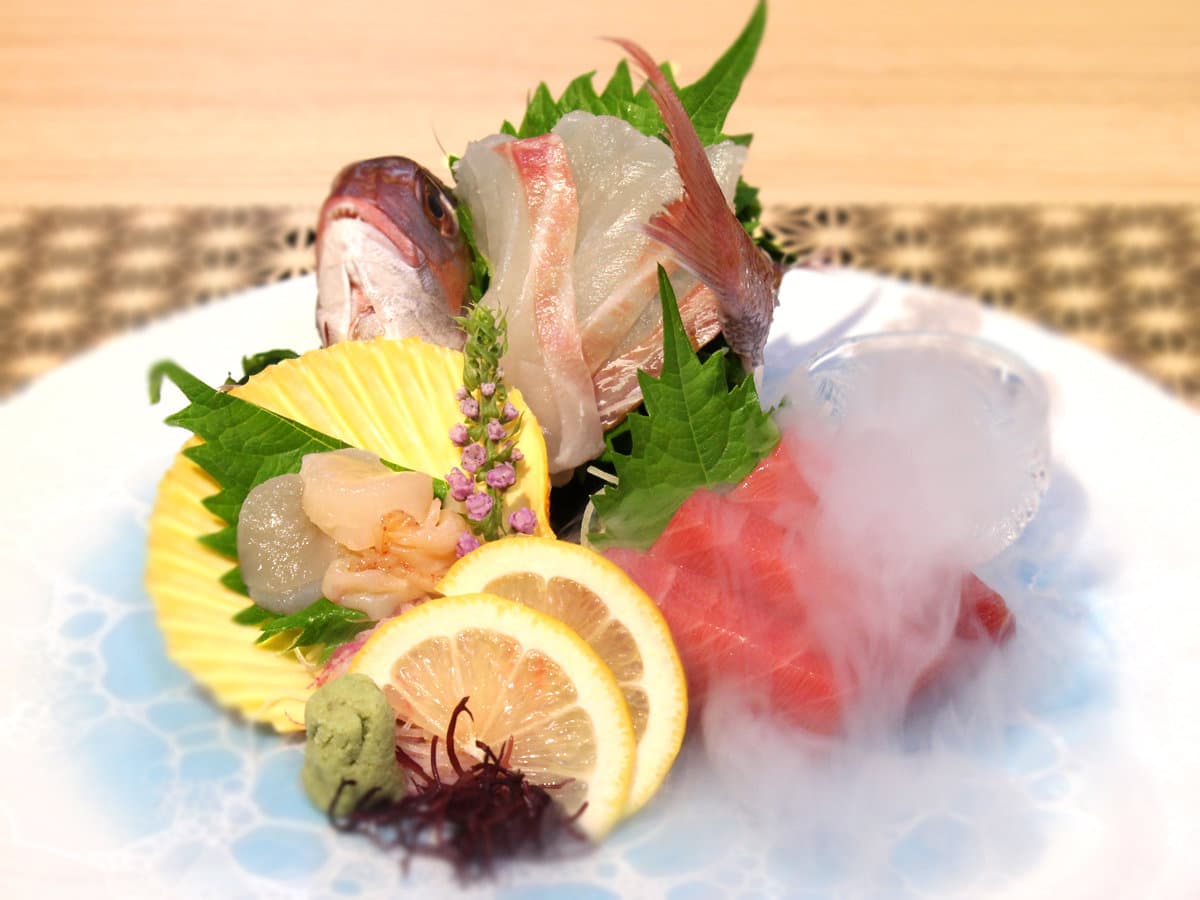 Plate of fresh local sashimi with citrus and dry-ice steam served at Yamanote Bettei Hagakure