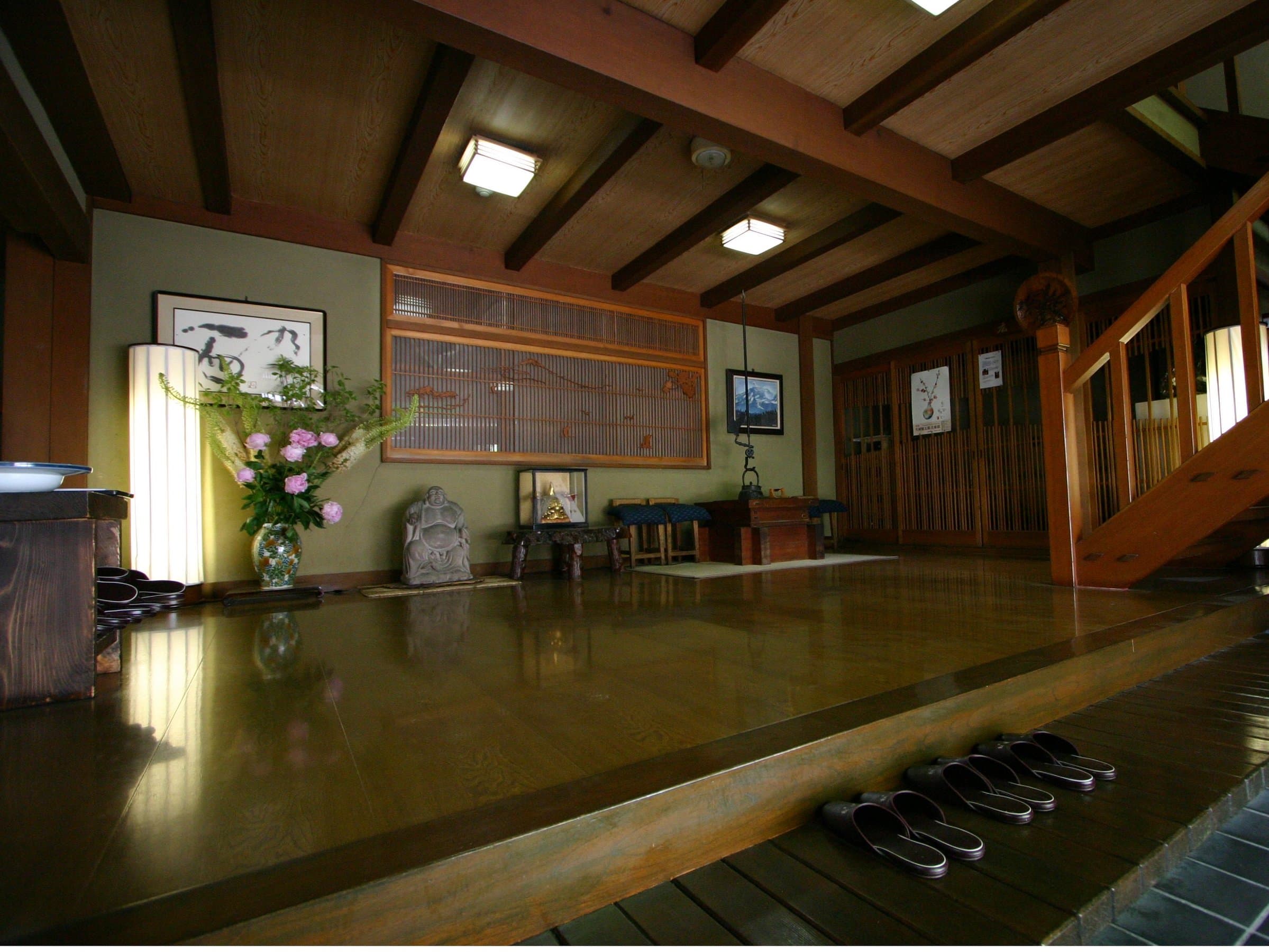 Traditional ryokan lounge and lobby with polished wood floor, exposed beams, flowers and seasonal decorations