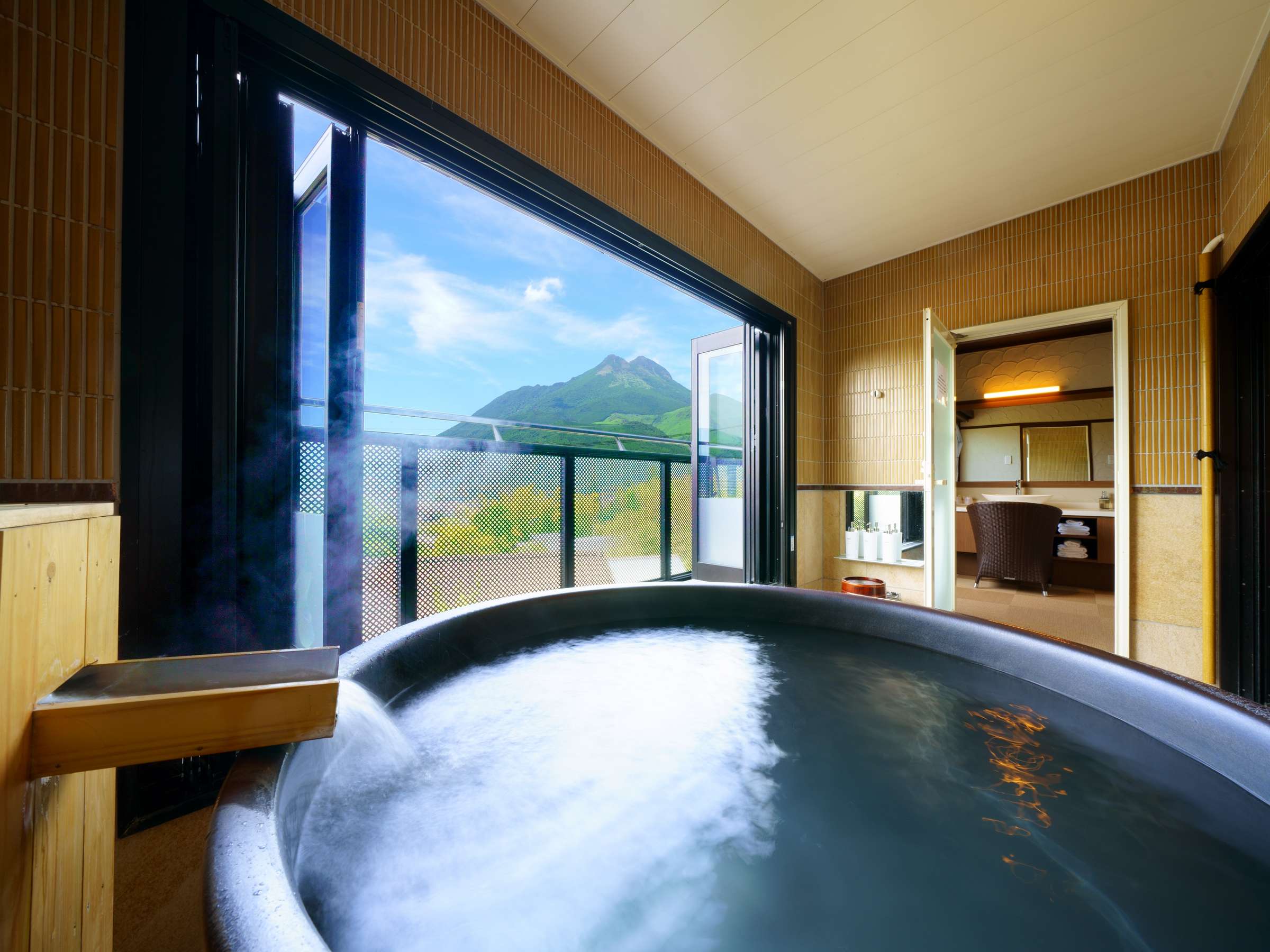 Private open-air bath at Bisei Yufuin with steaming round tub framing a view of Mount Yufu
