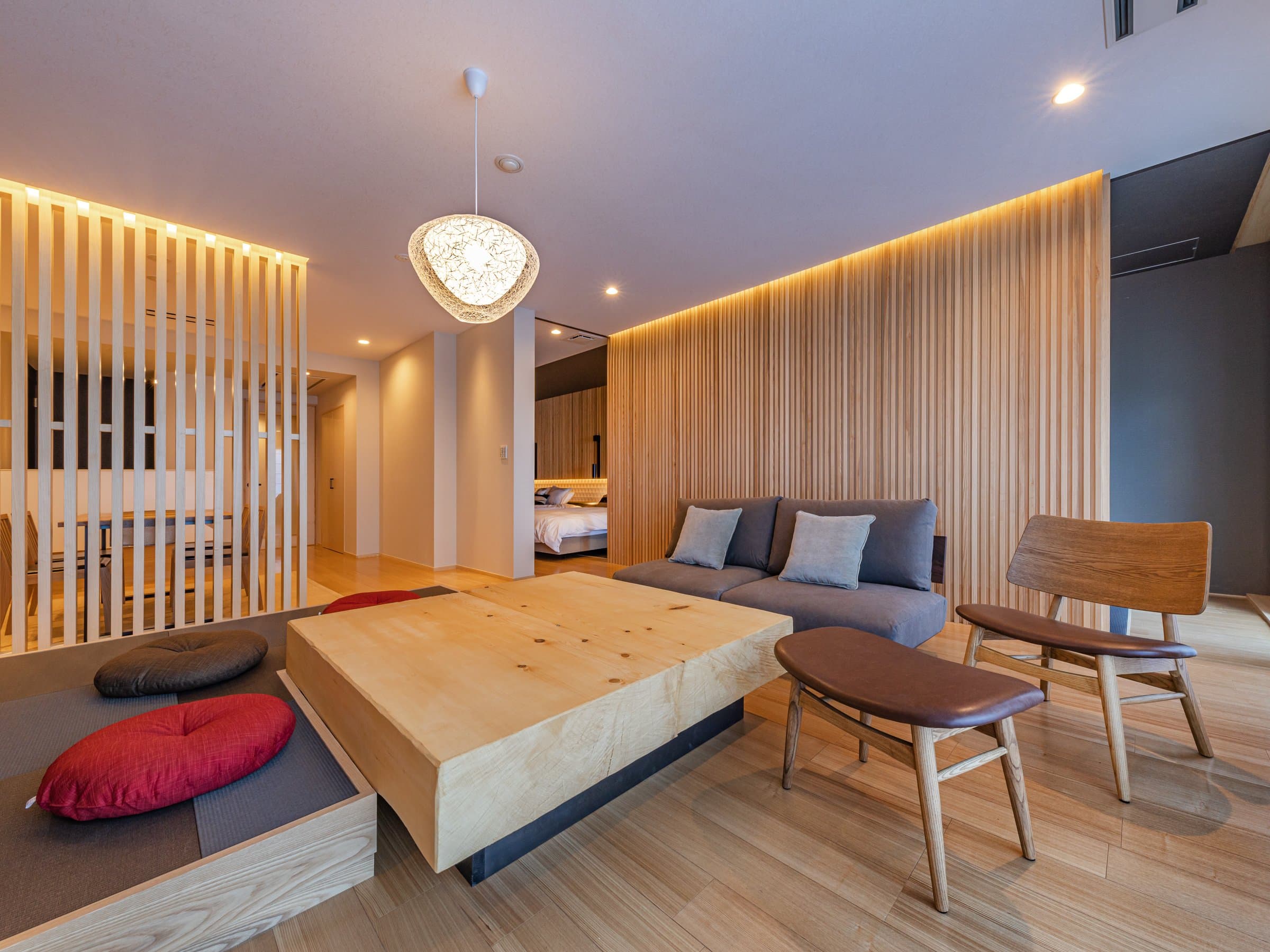 Modern suite living lounge with sunken seating, sofa and wood-slat walls at ISHINOYA Atami