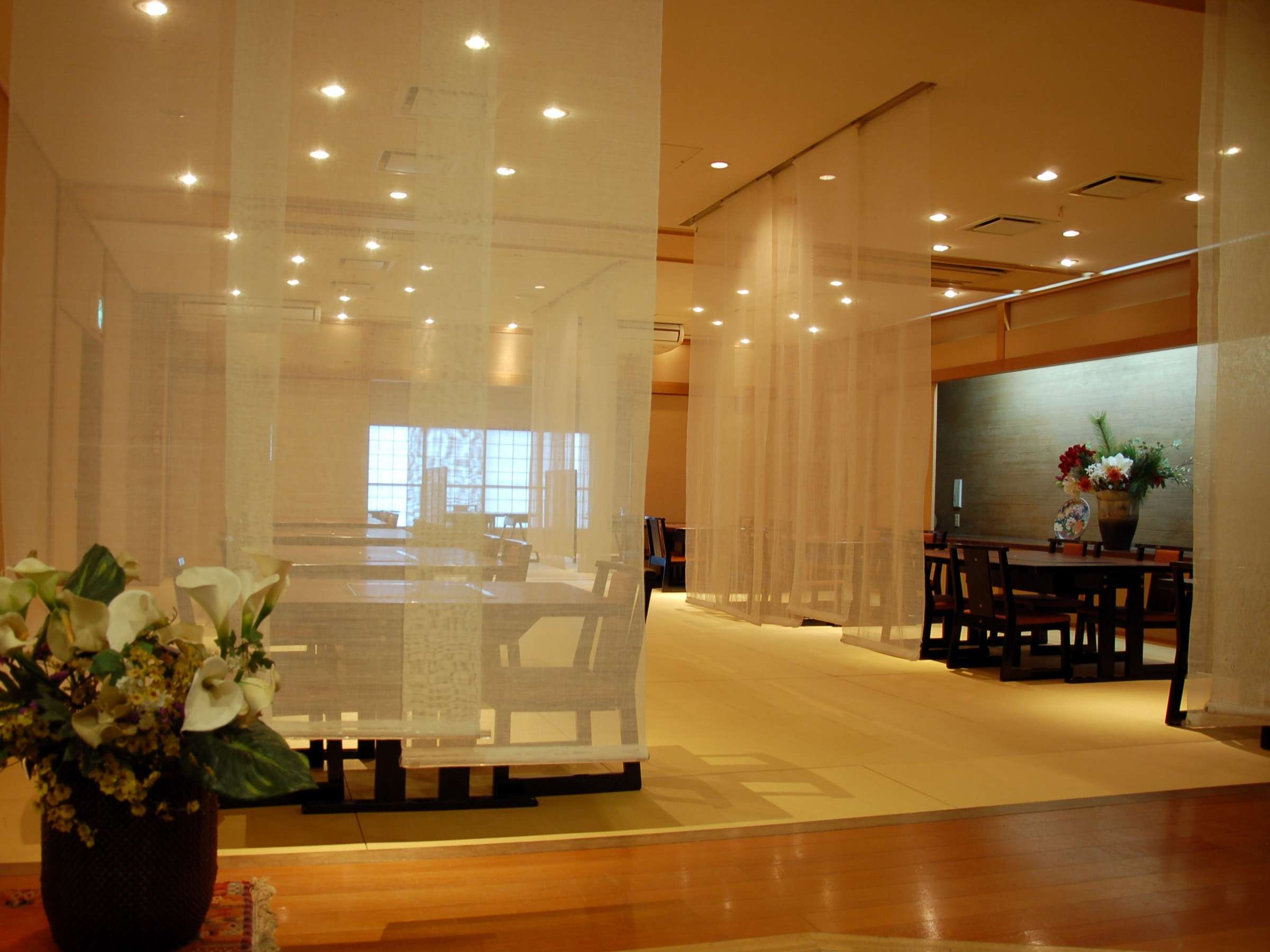 Lobby lounge with sheer linen partitions, lacquer tables and floral display at Tamanoyu ryokan in Noboribetsu Onsen