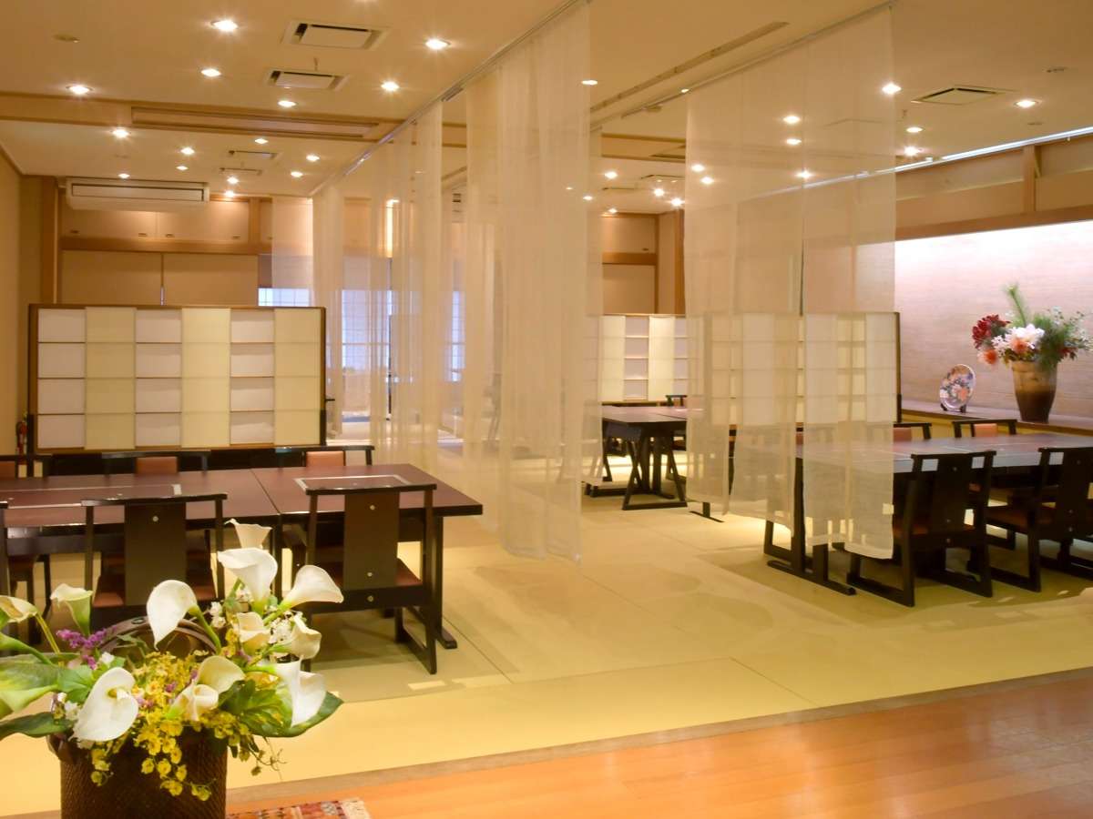 Japanese dining hall with low lacquer tables, sheer curtains and warm lighting at Tamanoyu ryokan, Noboribetsu