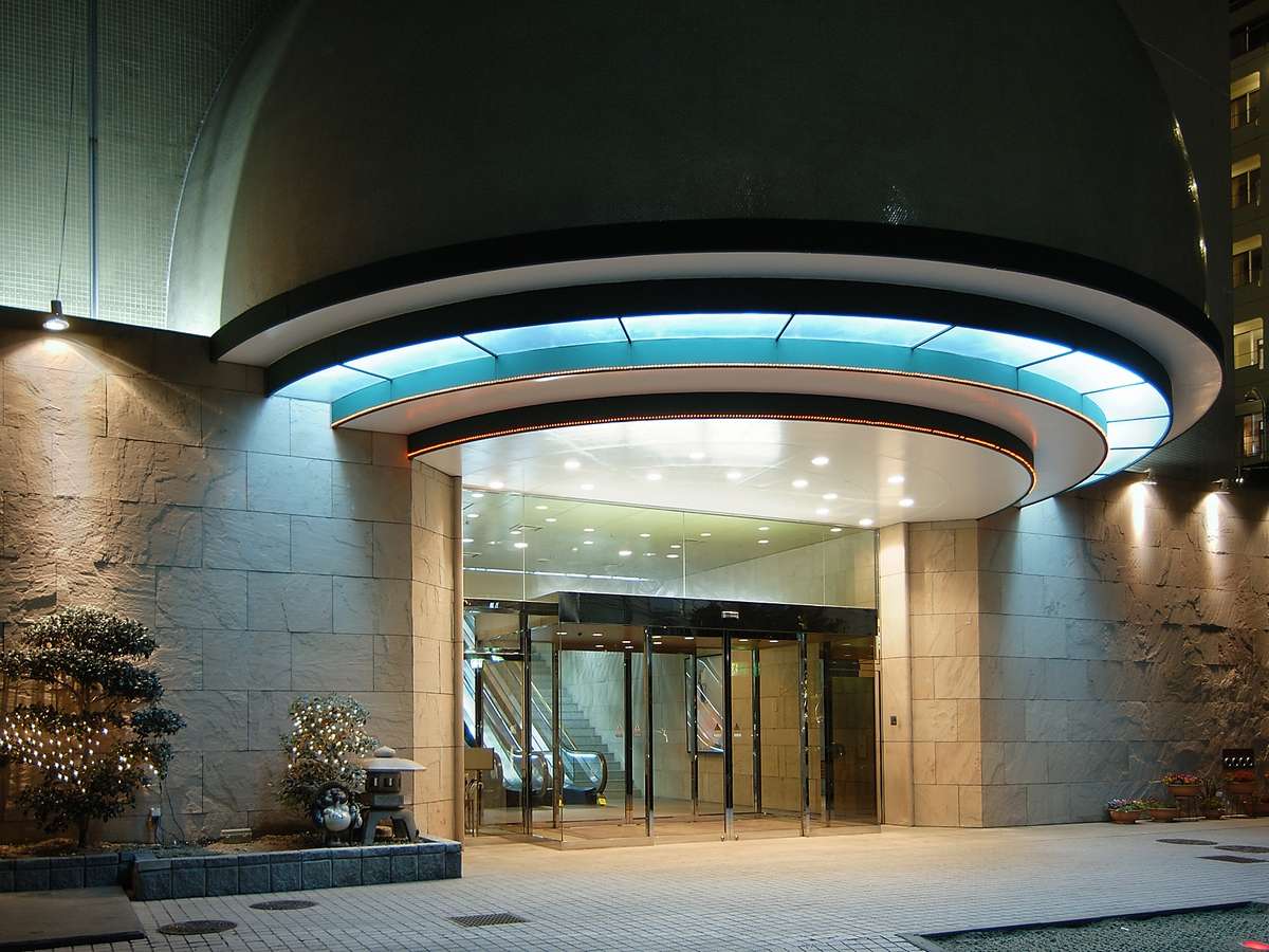 Illuminated curved porte-cochere entrance of Hotel Hanayuzuki glowing at night in Dogo Onsen